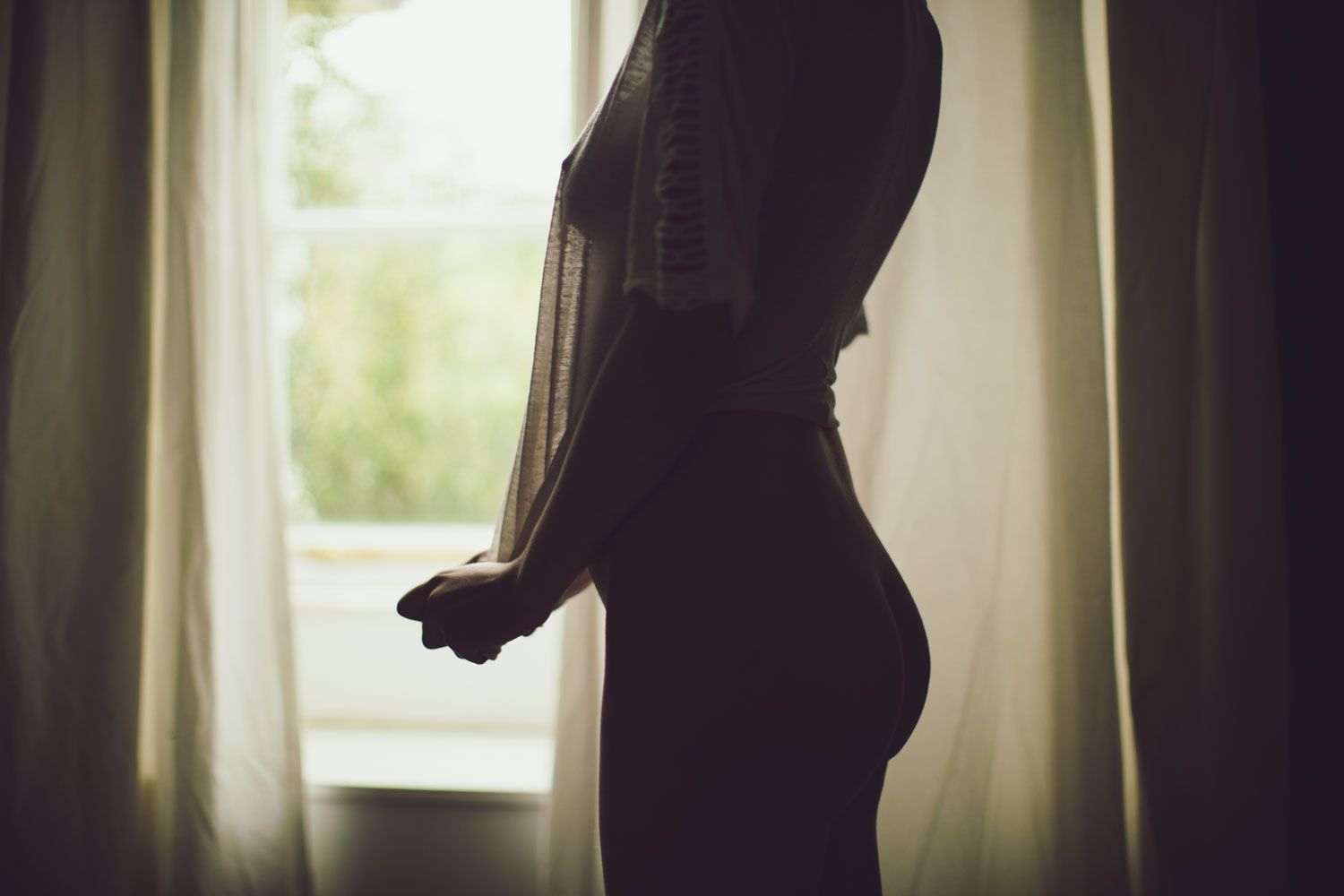Fine art photograph of the female form in soft natural light, face hidden.