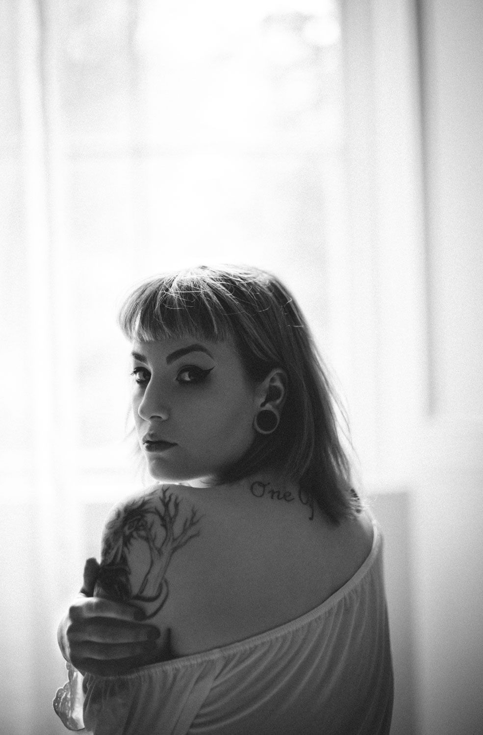 Black and white over the shoulder portrait of a woman gazing into the camera, fine art photography in Dublin Ireland.