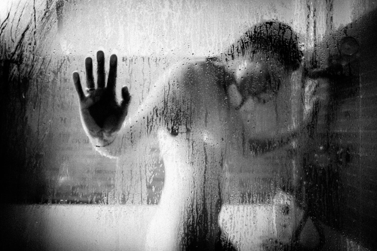 Artistic body composition in shower with soft gradients of light and shadow.