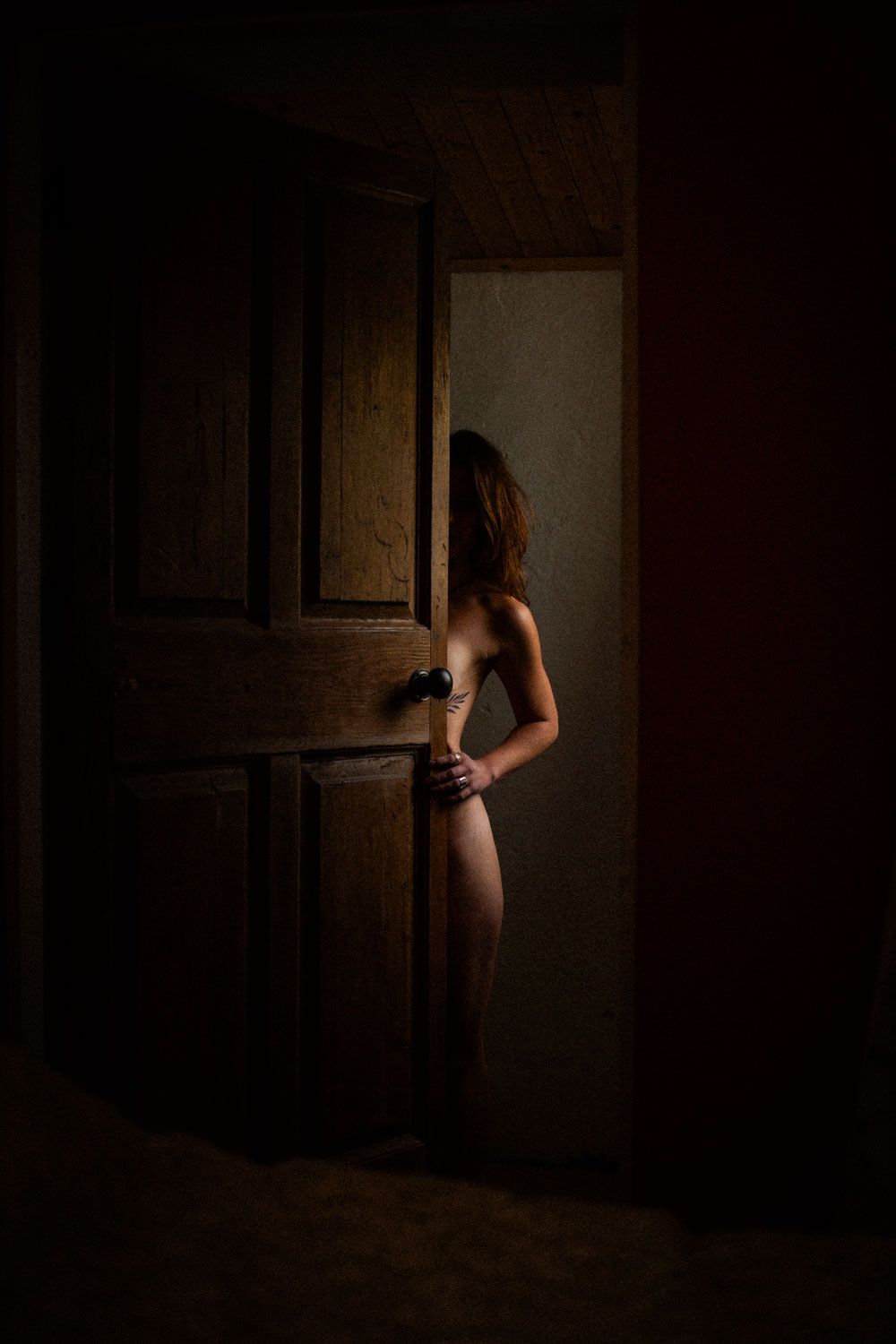 Artistic nude-inspired body photograph hiding behind door showcasing elegant lines and contours.