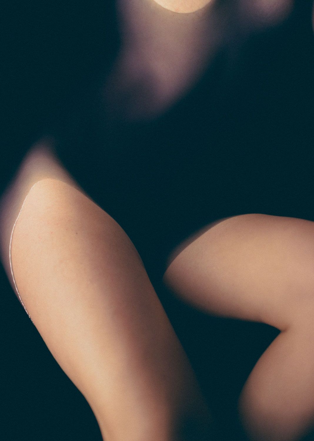 Artistic body composition in dark water with soft gradients of light and shadow.