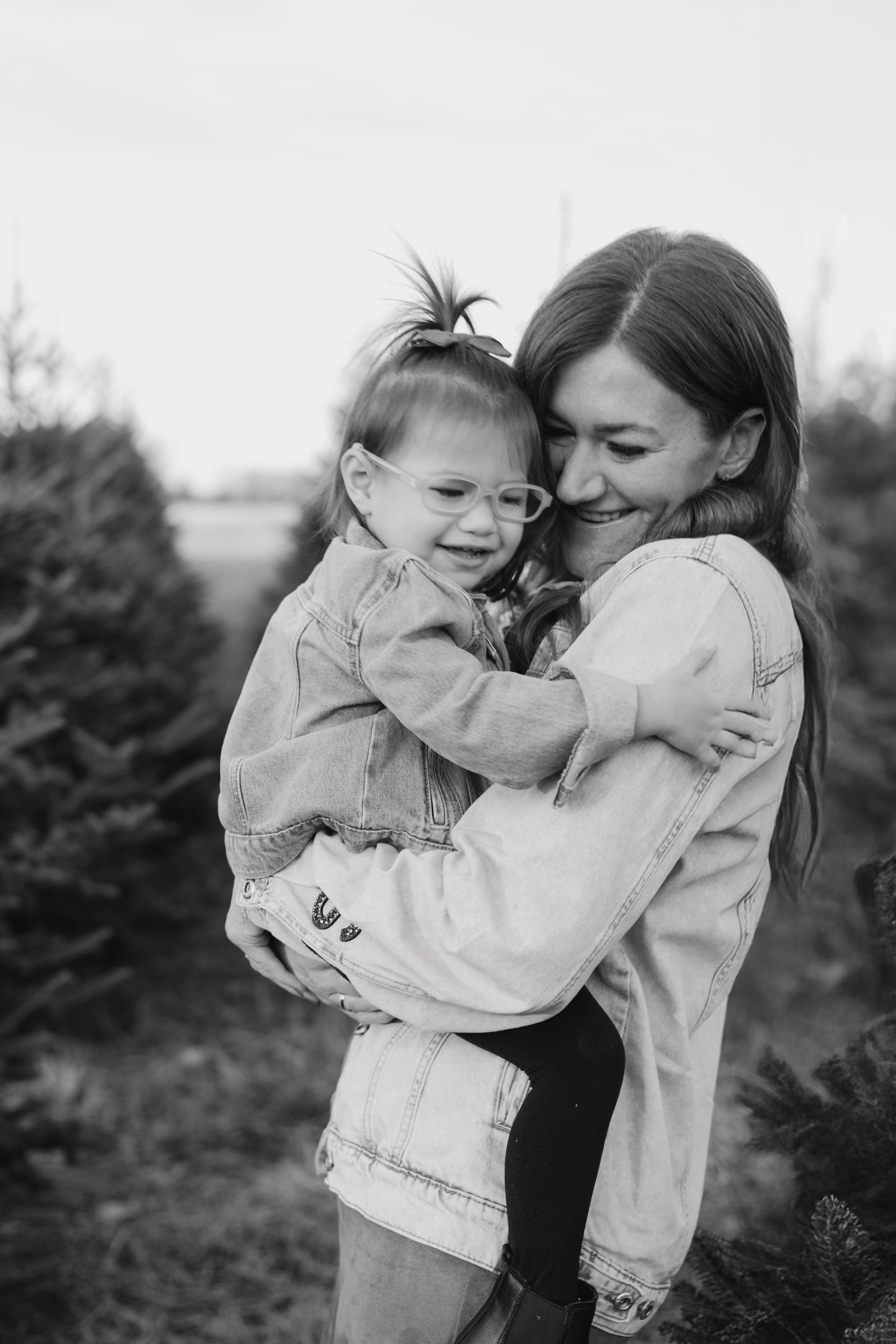 A heartwarming black and white portrait of a mother and young child sharing a joyful embrace outdoors.