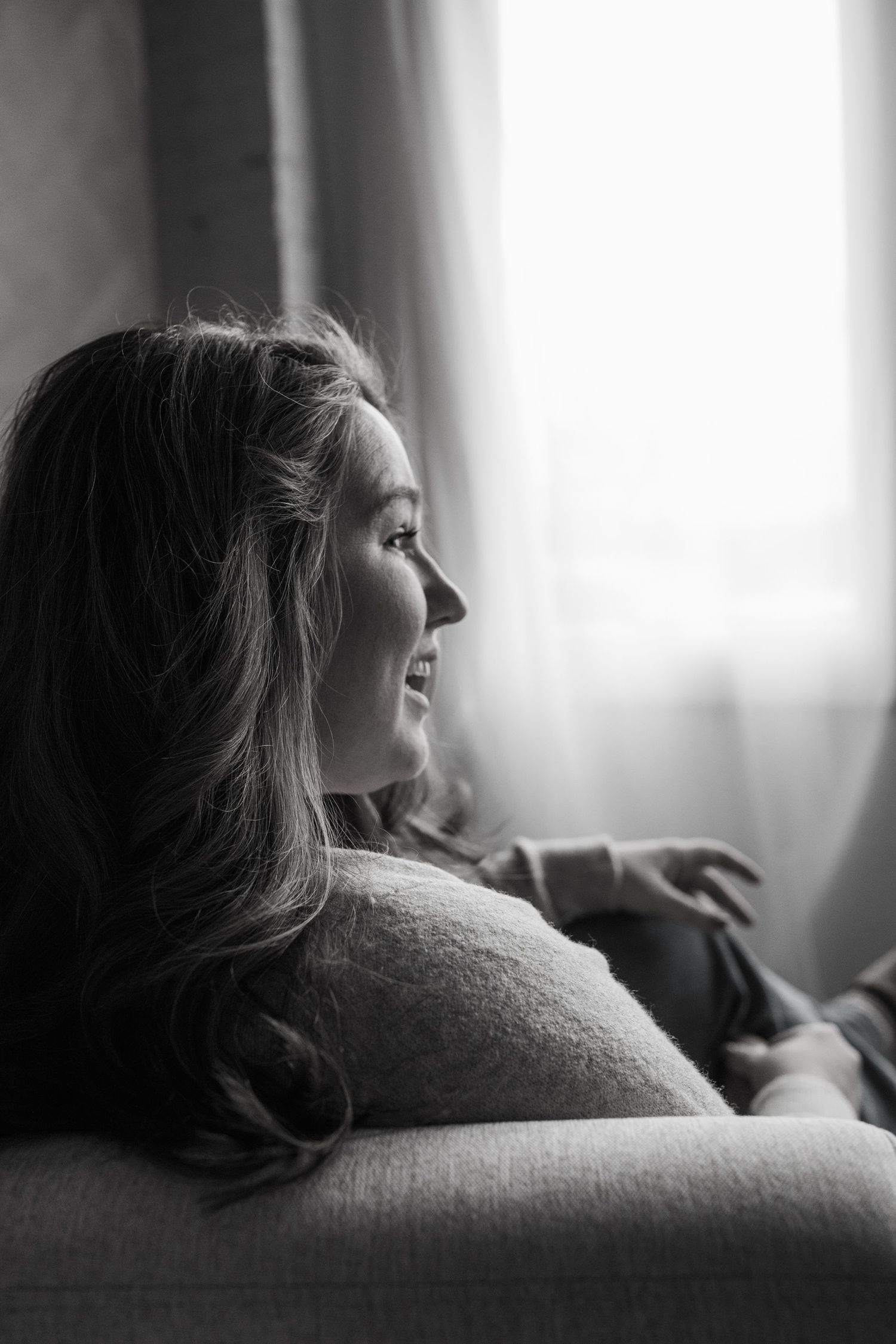 Black and white profile portrait of person relaxing on couch near window.