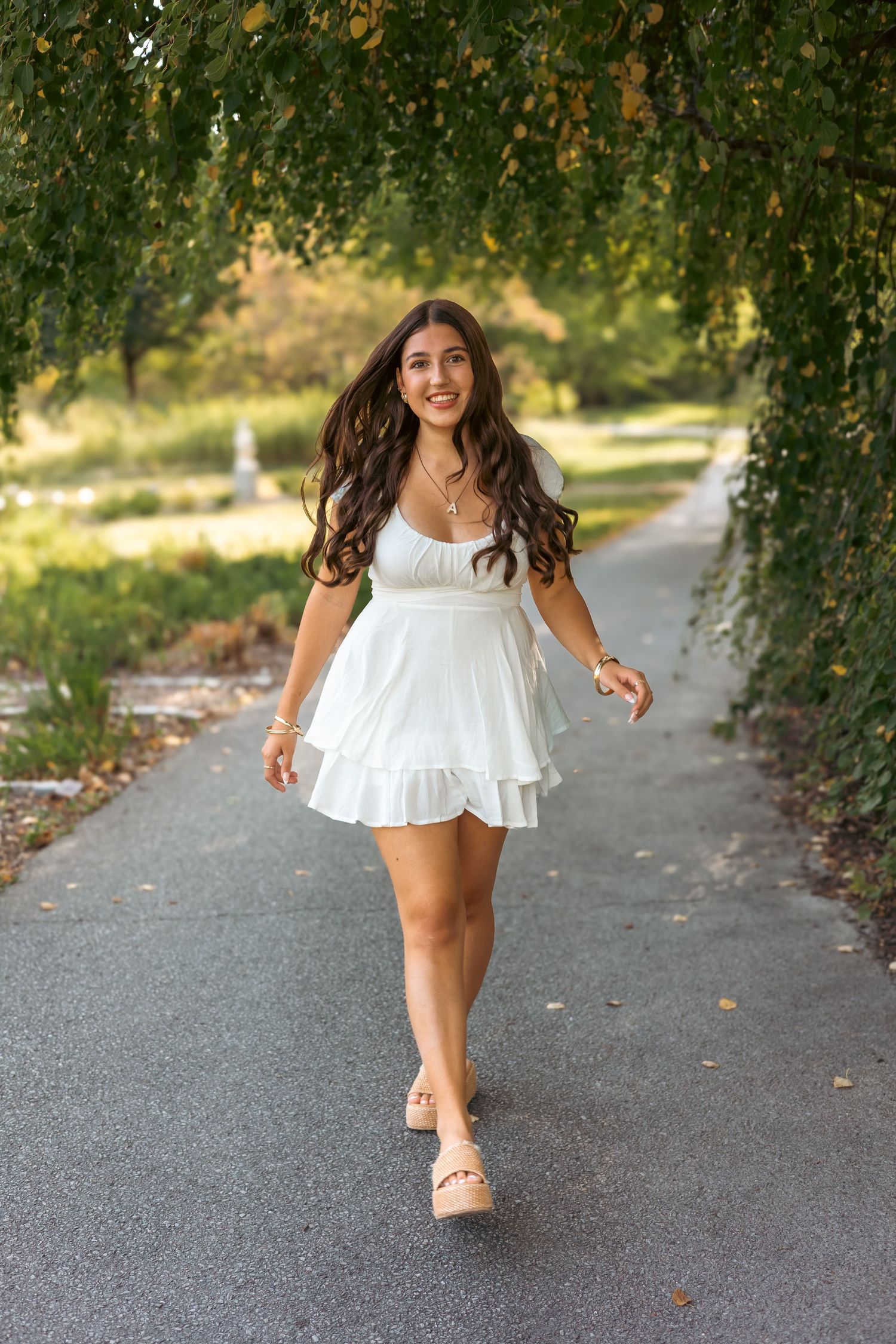 A sequence of photos shows someone in a white flowing dress walking along a tree-lined path on a sunny day.