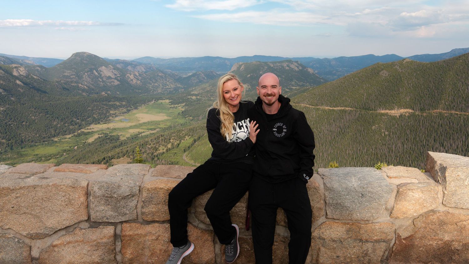 Jon & Heather Penton of Wolfpack Wedding Co at a Rocky Mountain National Park overlook. Smiling husband-wife adventure photo team.