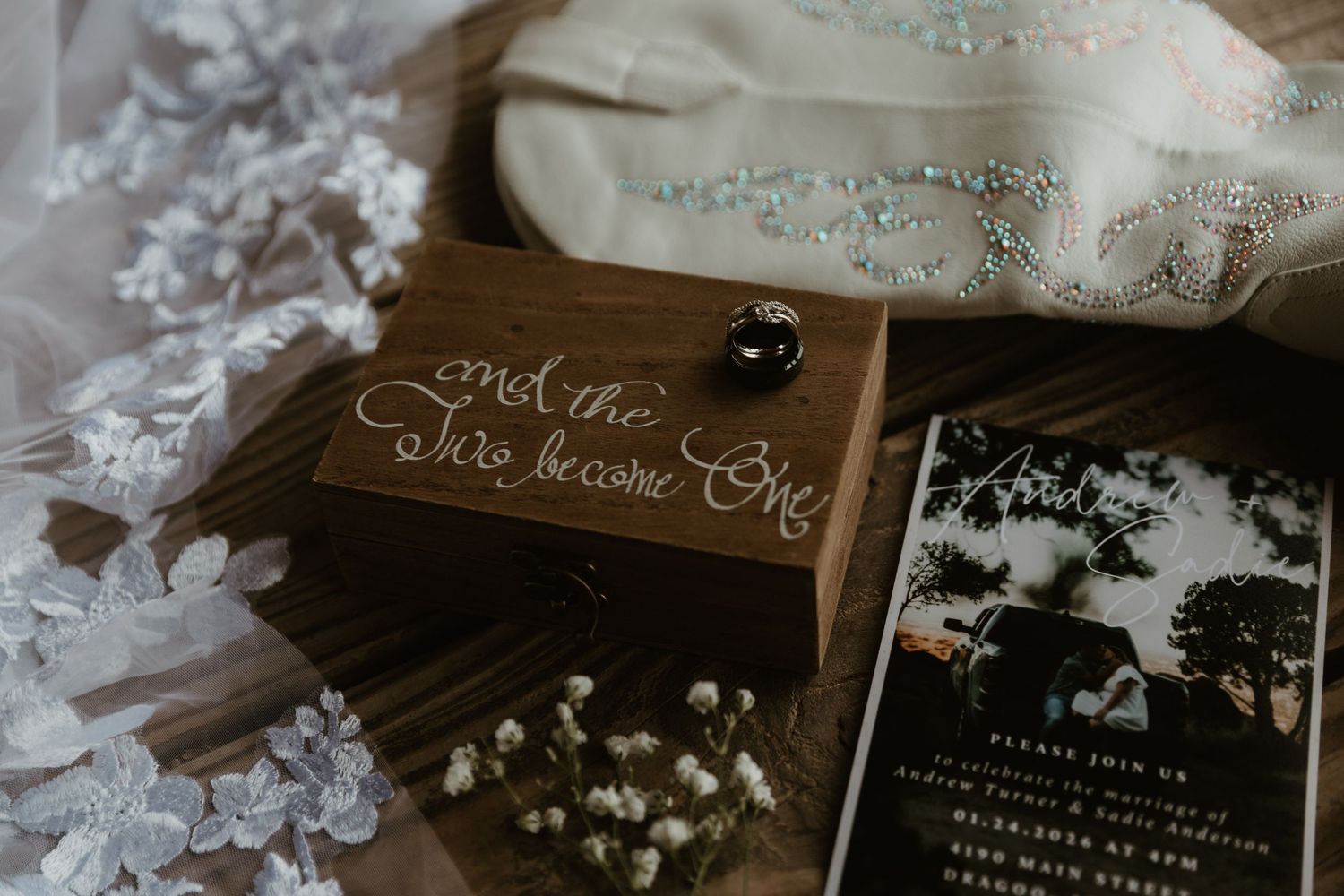 Elegant black and white wedding invitation suite with floral details and delicate lace accents displayed on wooden surface. Tucson Weddings.