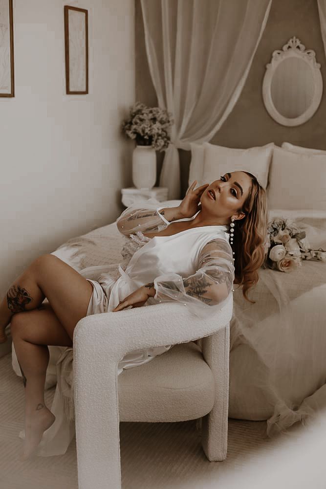 Artistic boudoir photo series in sepia tones showing a figure reclining on white furniture in elegant poses. Tucson couples boudoir.