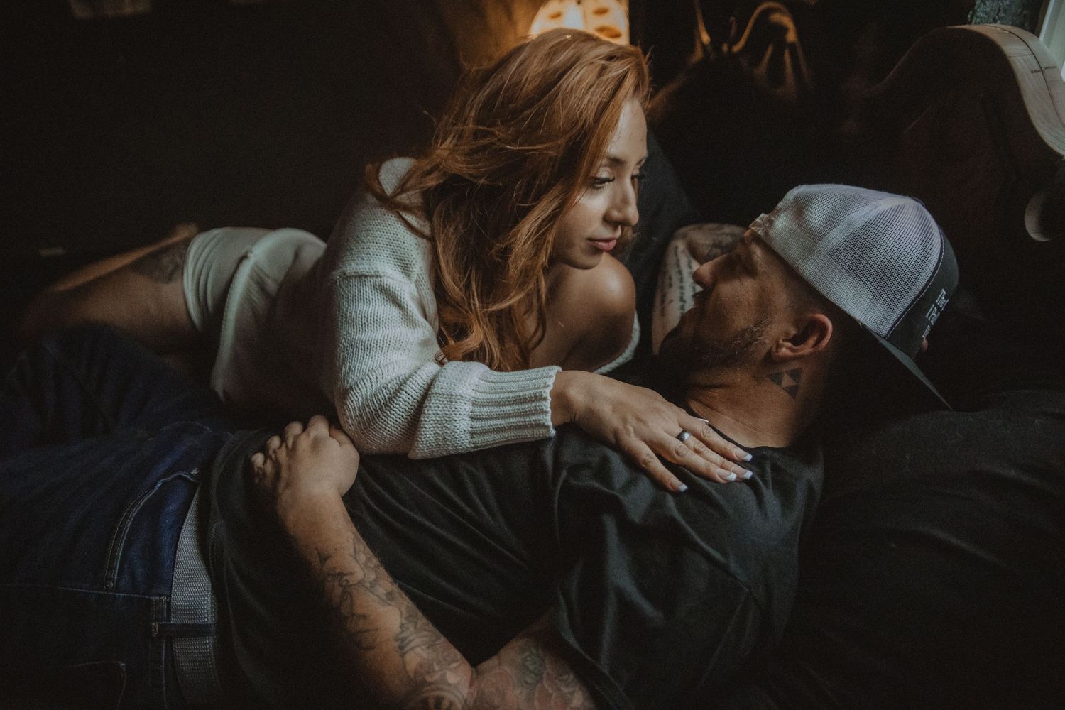 A couple shares an intimate romantic moment together in a dark, moody setting. Tucson couples boudoir.
