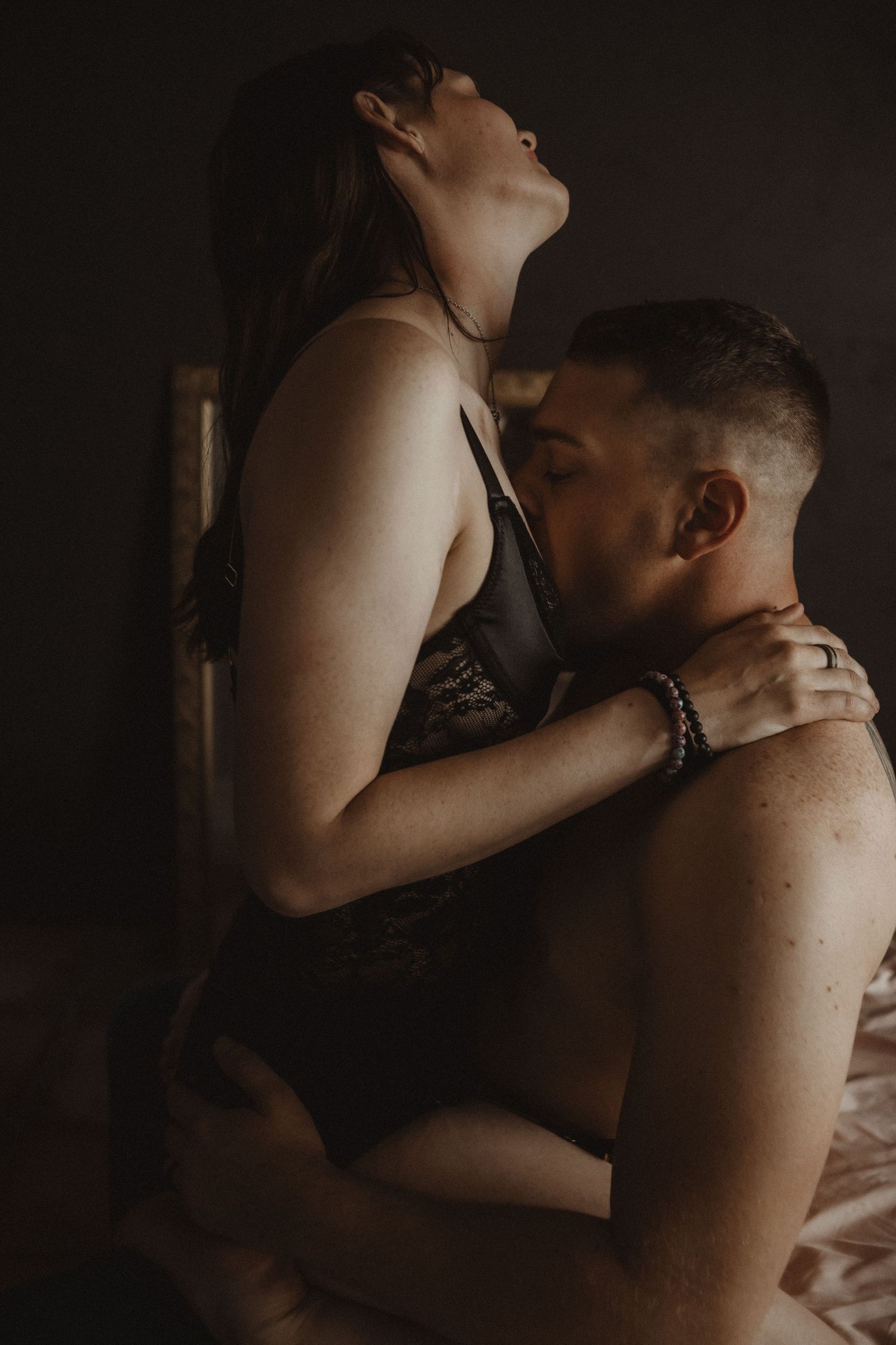 Intimate black and white photo series showing a couple embracing in low light with dramatic shadows. Tucson couples boudoir.