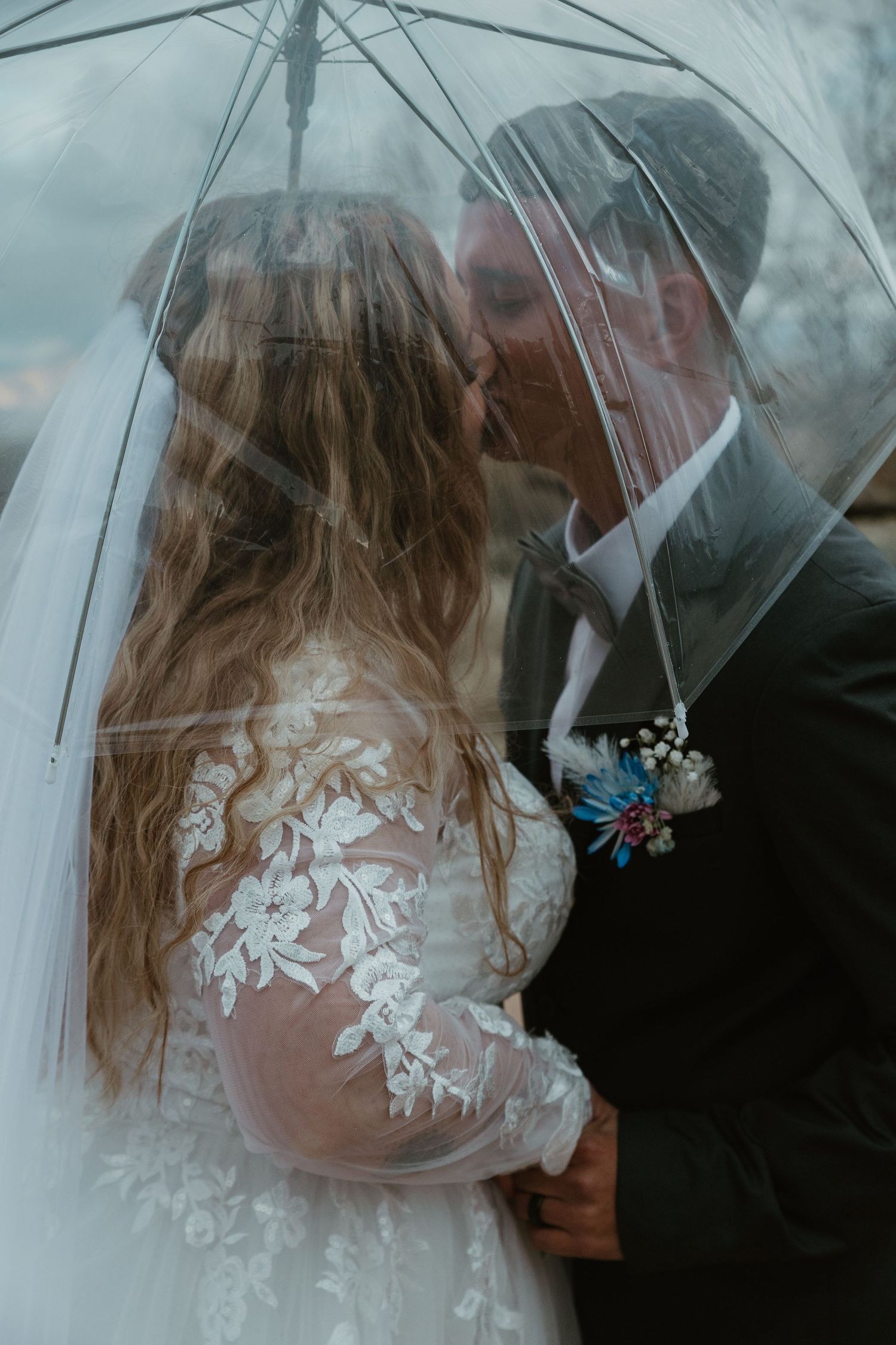 A romantic wedding couple shares an intimate moment under a clear umbrella on a misty day. Tucson elopement photographer.