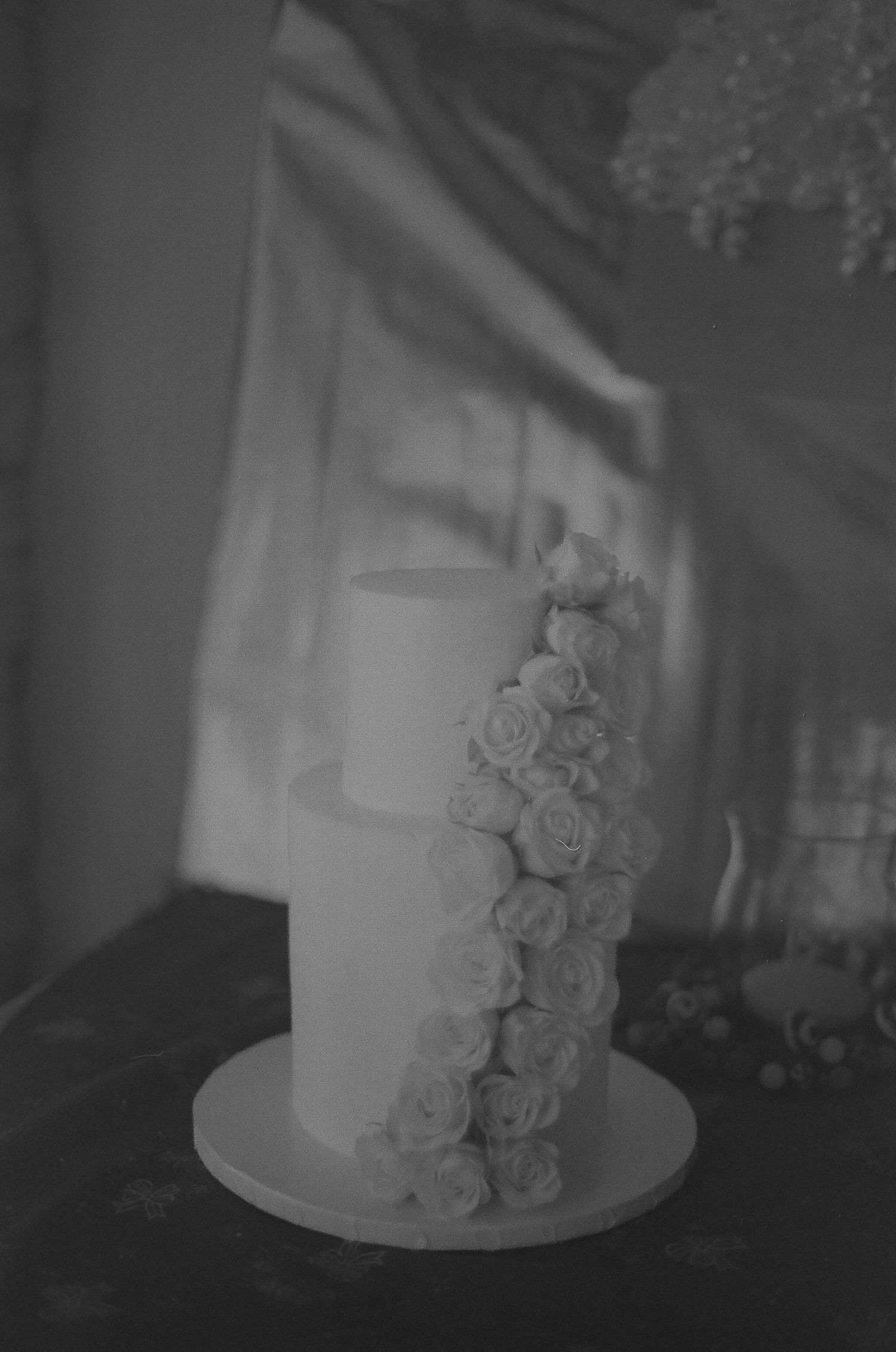 A black and white wedding cake decorated with cascading white roses against a dark background. Tucson Wedding photographer