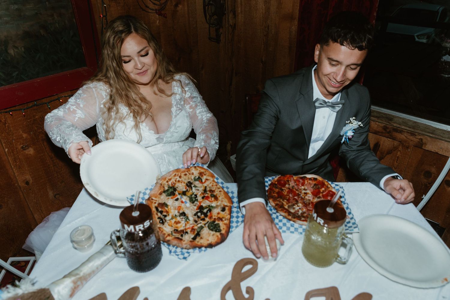 Guests enjoying a formal dinner reception with plates of food and drinks at a rustic wooden table. Tucson elopement photographer.