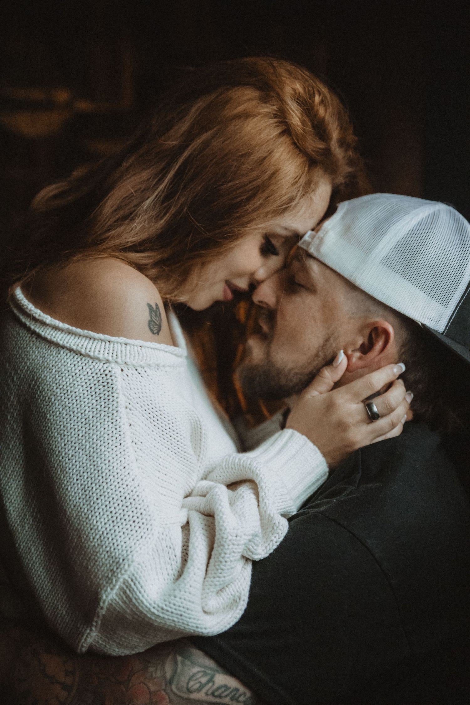Intimate series of dark moody photographs showing couple in white sweater embracing in dramatic lighting. Tucson couples boudoir.