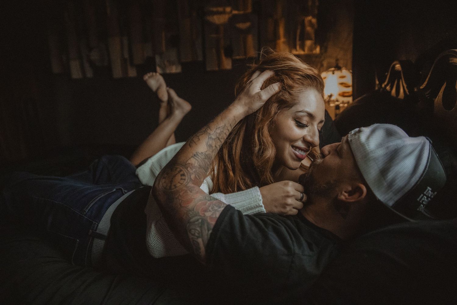 A romantic couple shares an intimate moment in low-light conditions with warm ambient lighting. Tucson couples boudoir.