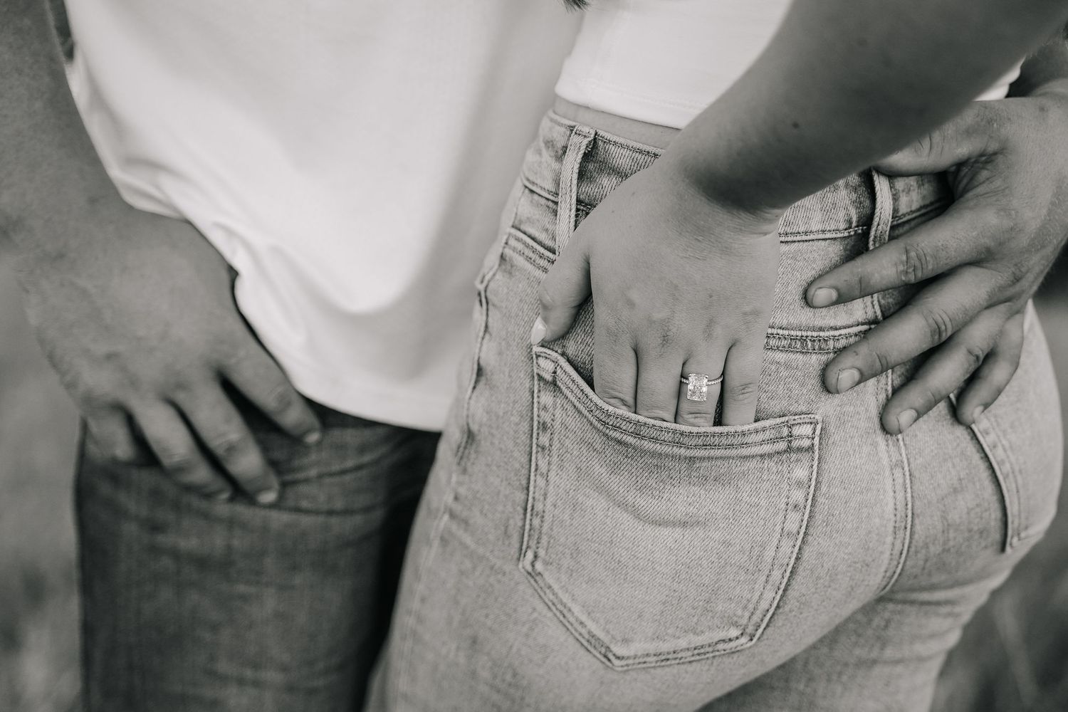 Black and white close-up of a couple holding each other by the waist in jeans.