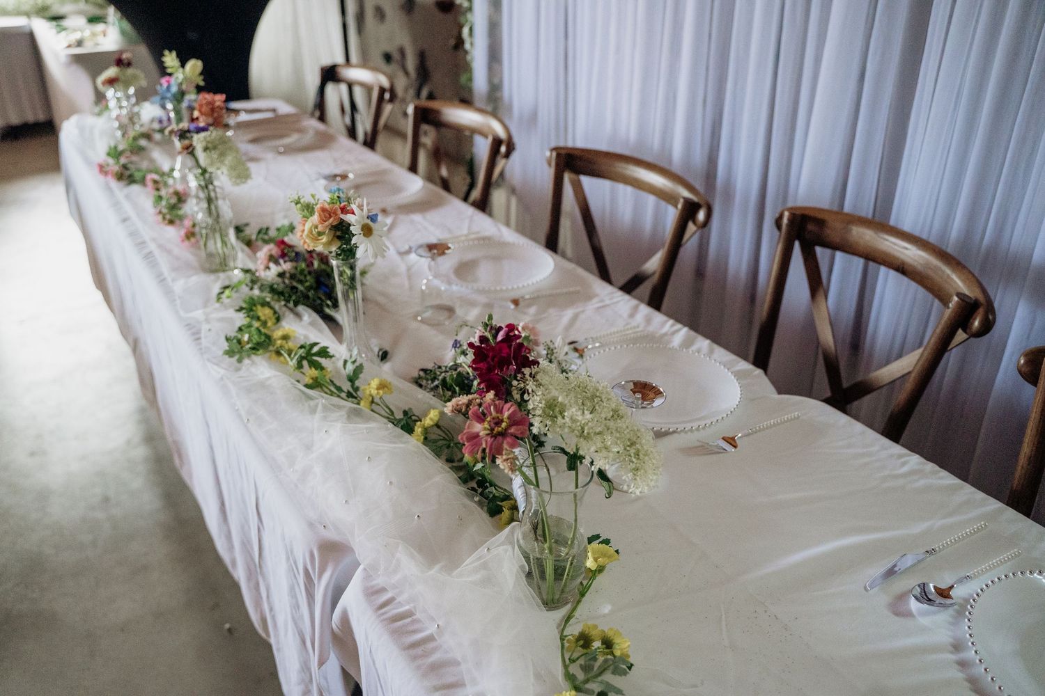 Elegant wedding head table with floral centerpieces and white tablecloth.