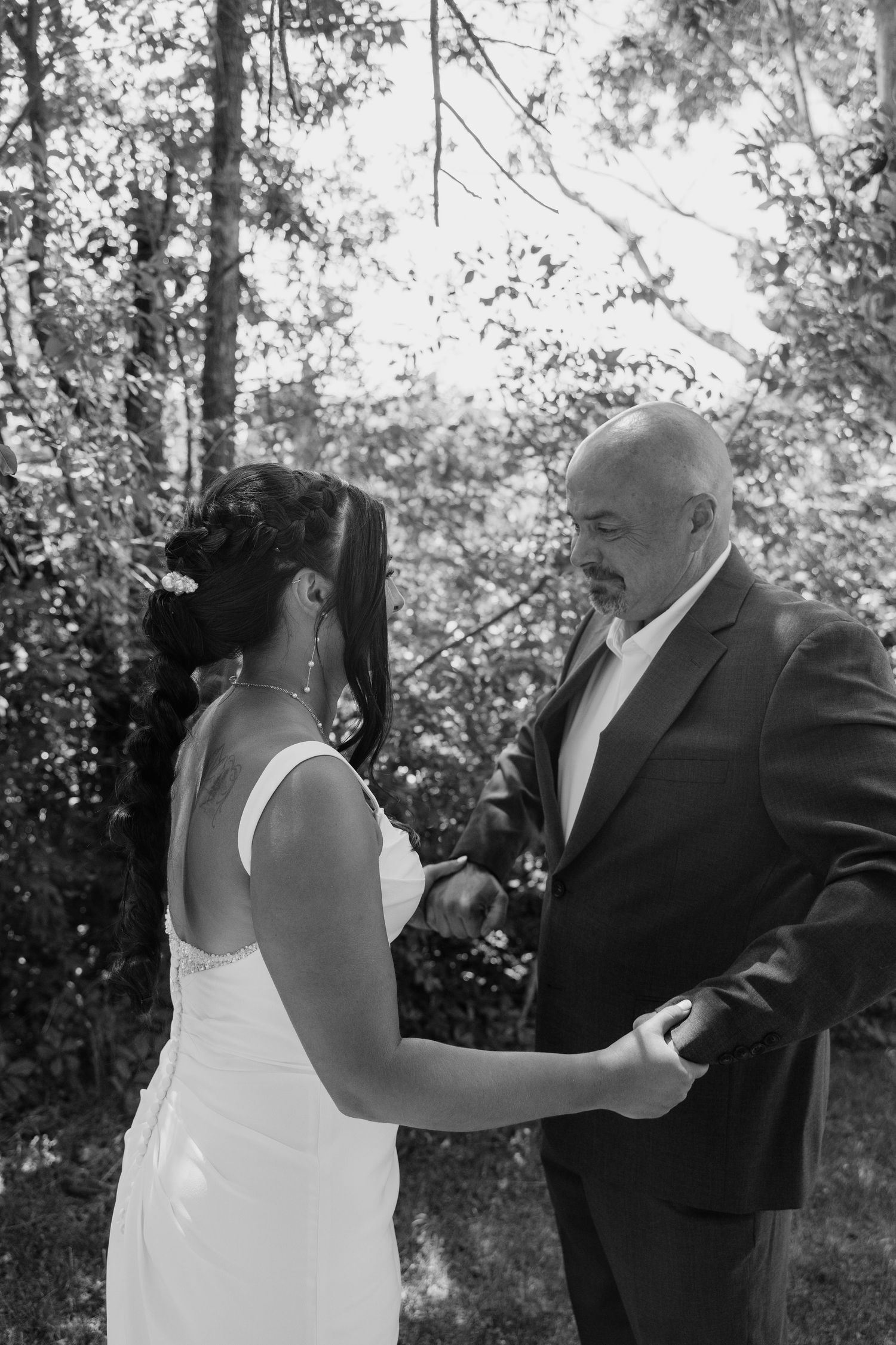 Black and white photo of a bride and her father sharing a tender first look moment outdoors.