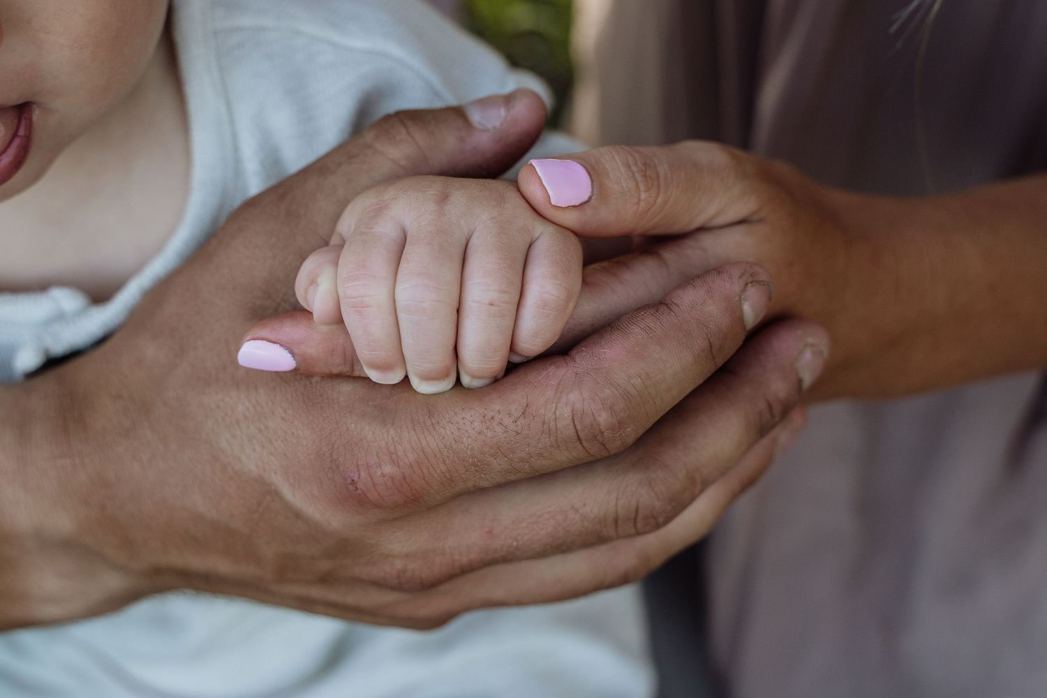 Adult hands gently cradling a newborn baby's tiny hand, symbolizing love and family bonding.