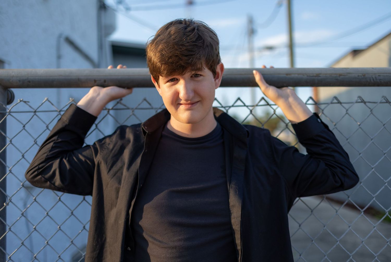 A series of five similar photos showing someone posing against a chain link fence with a blue sky background.