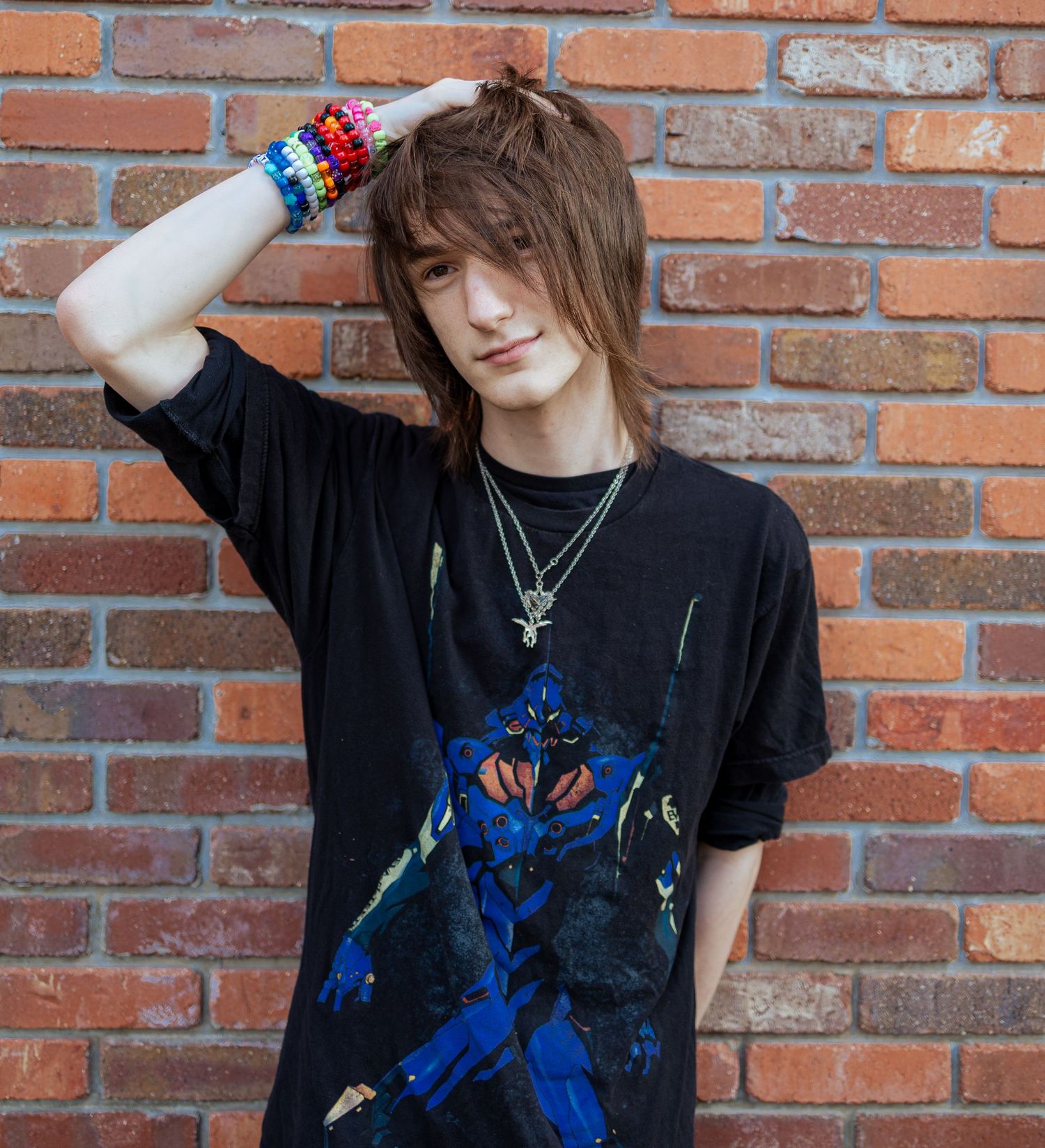 Person in black t-shirt with blue graphic design poses against brick wall in artistic photo series.