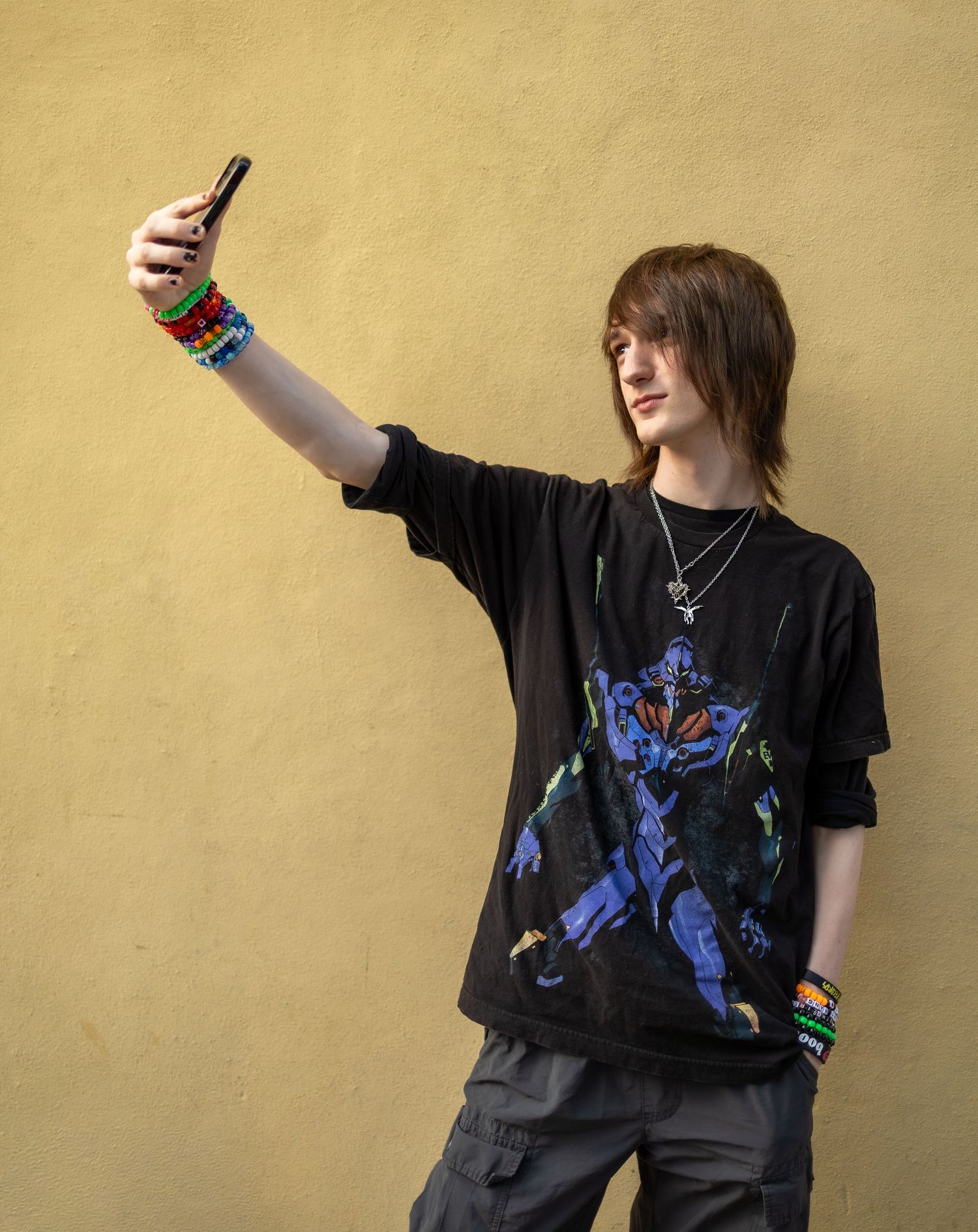 Person in black t-shirt with blue graphic strikes dynamic poses against yellow wall wearing dark pants.
