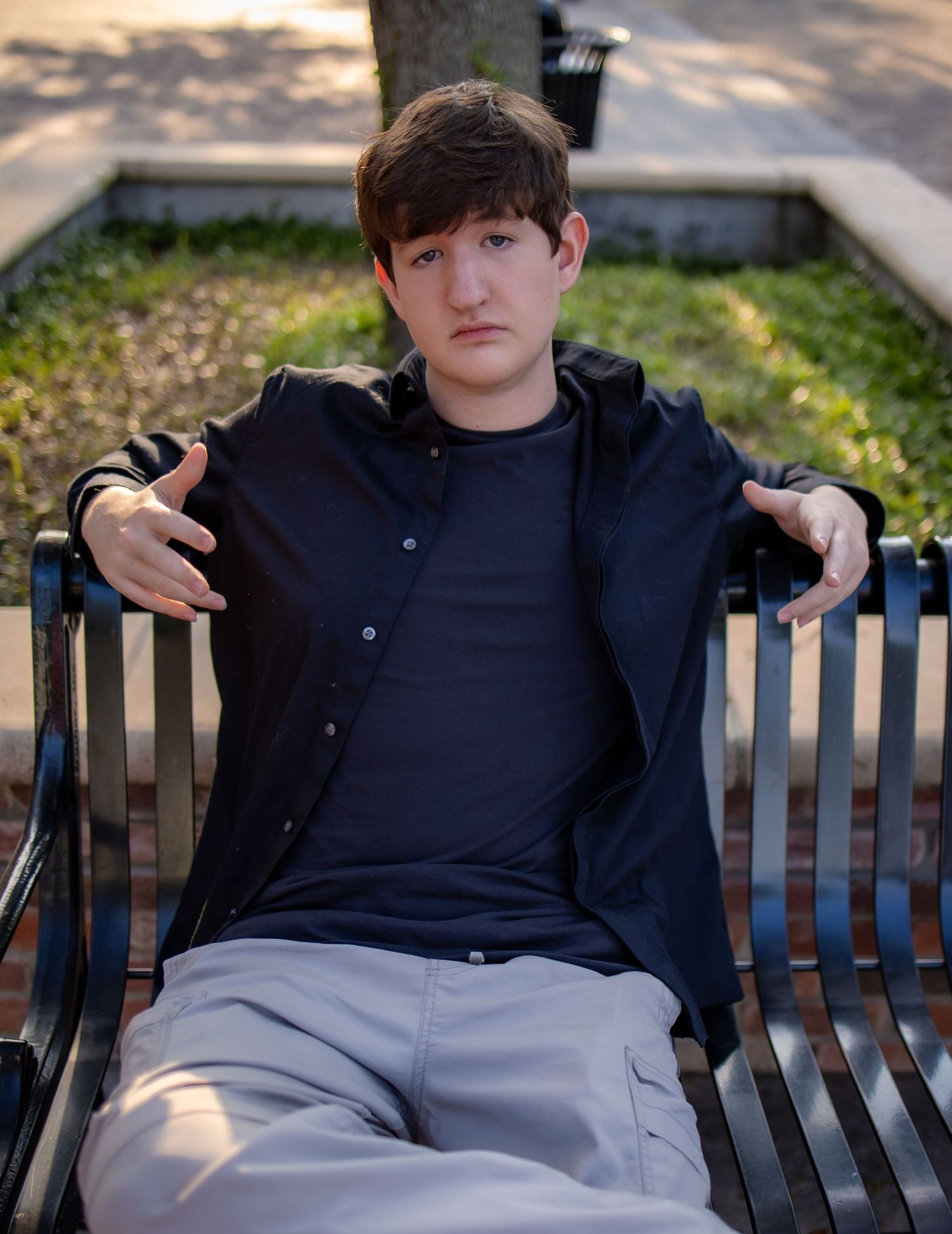 Person sitting on wooden bench in casual attire during golden hour lighting.