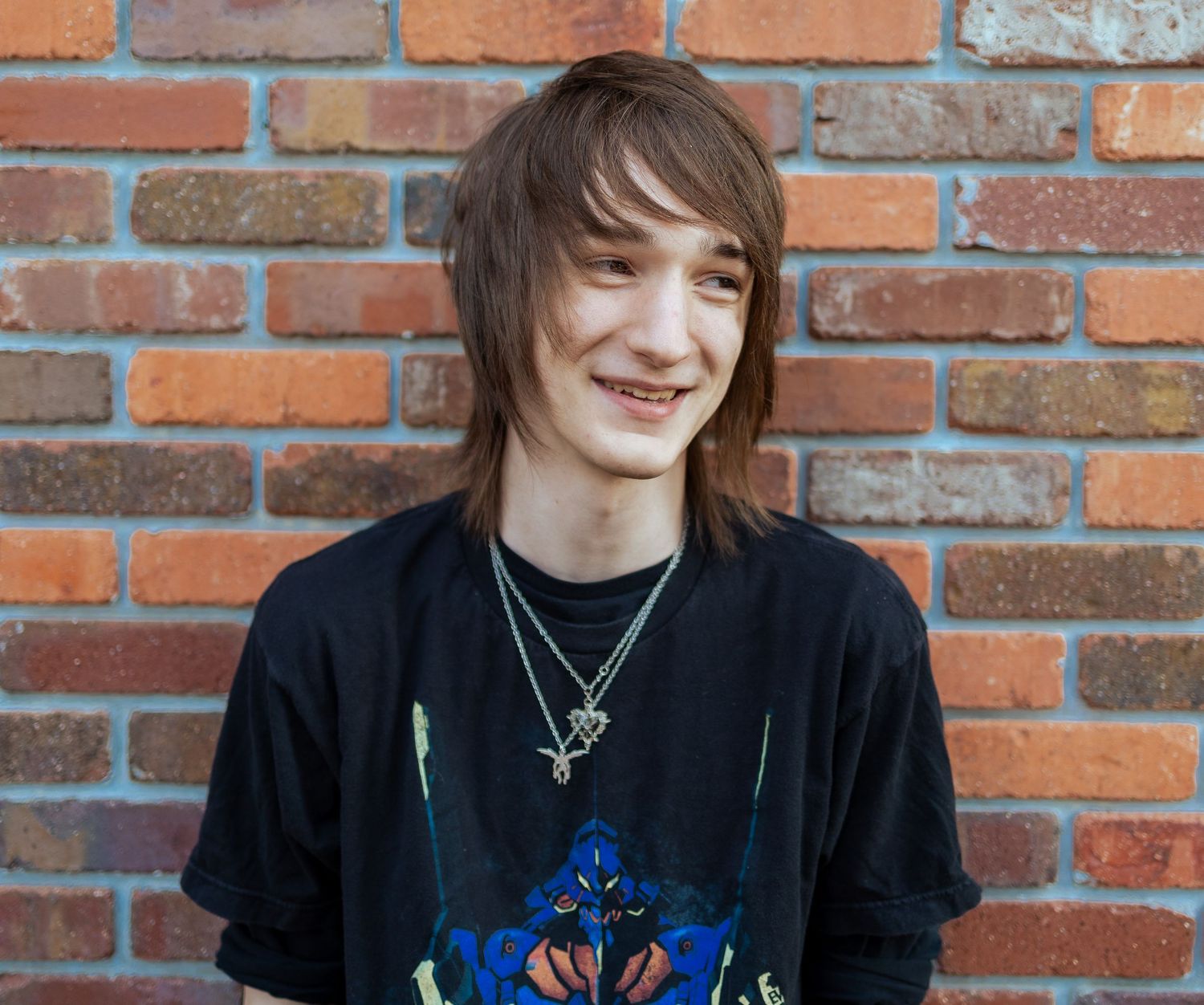 A person in a black shirt with brown hair stands against a brick wall, shown in four similar poses.