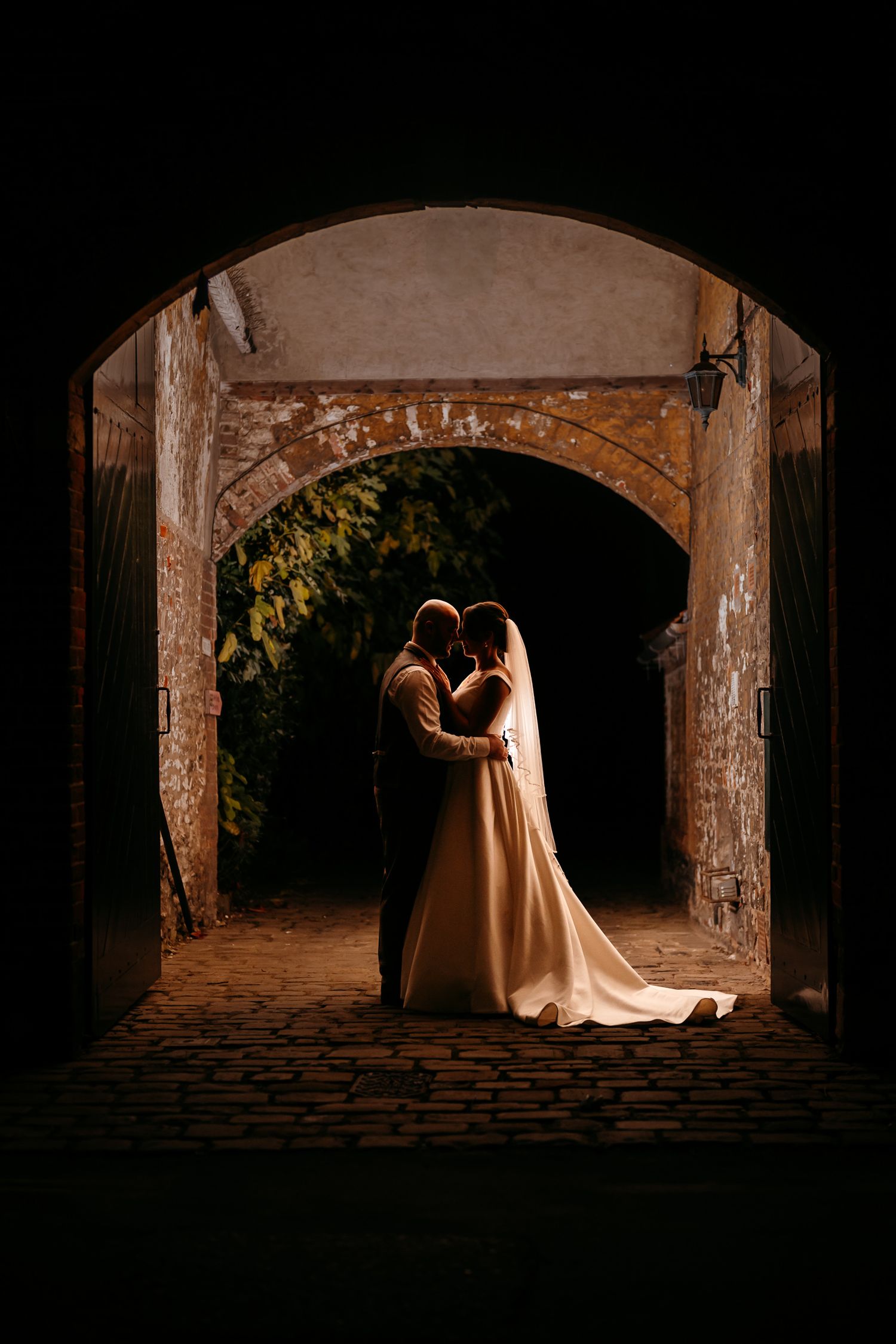 Couple under a stone arch with specialist night photography lighting.