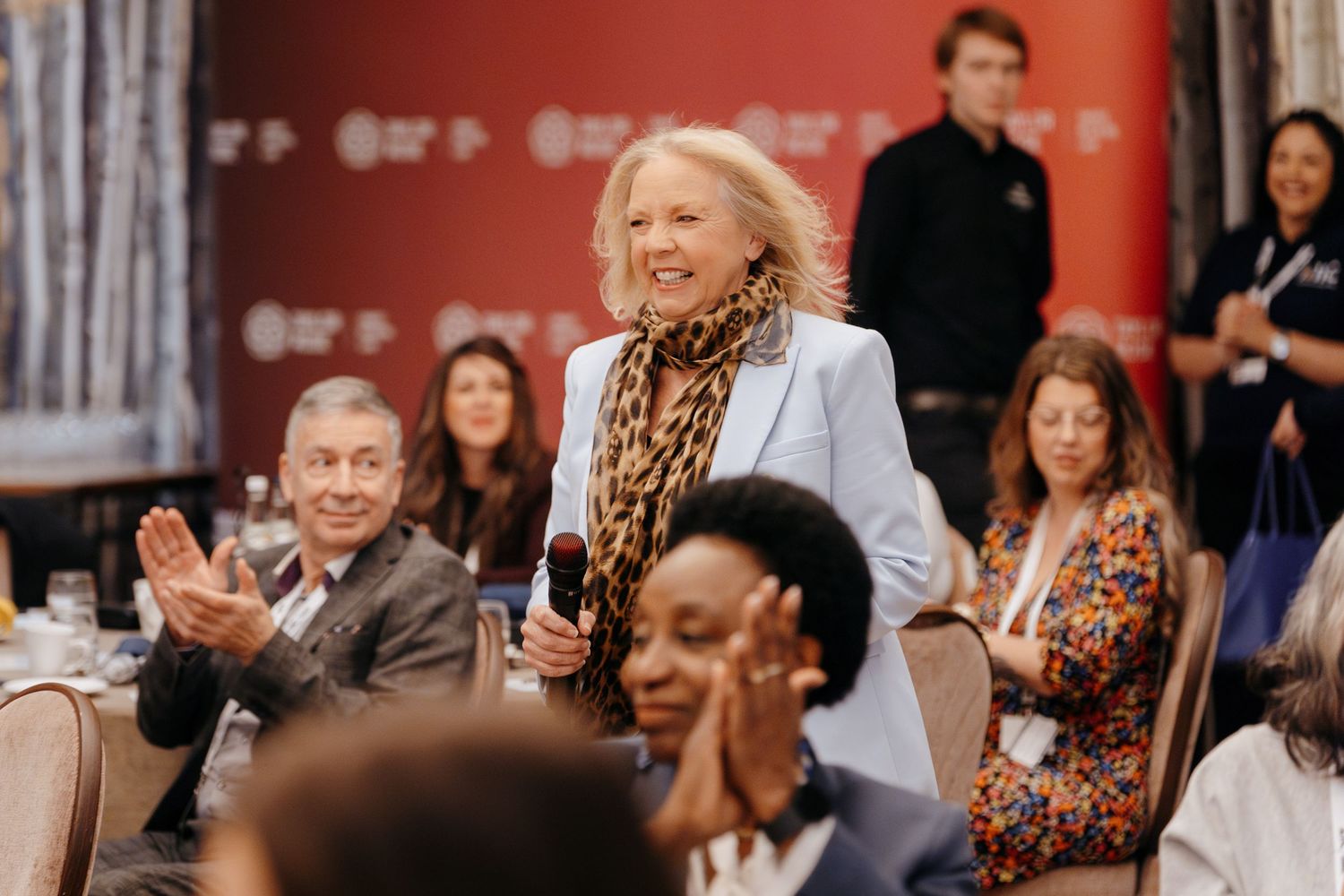 Guest speaker walking on stage at a large conference event in Cambridge.