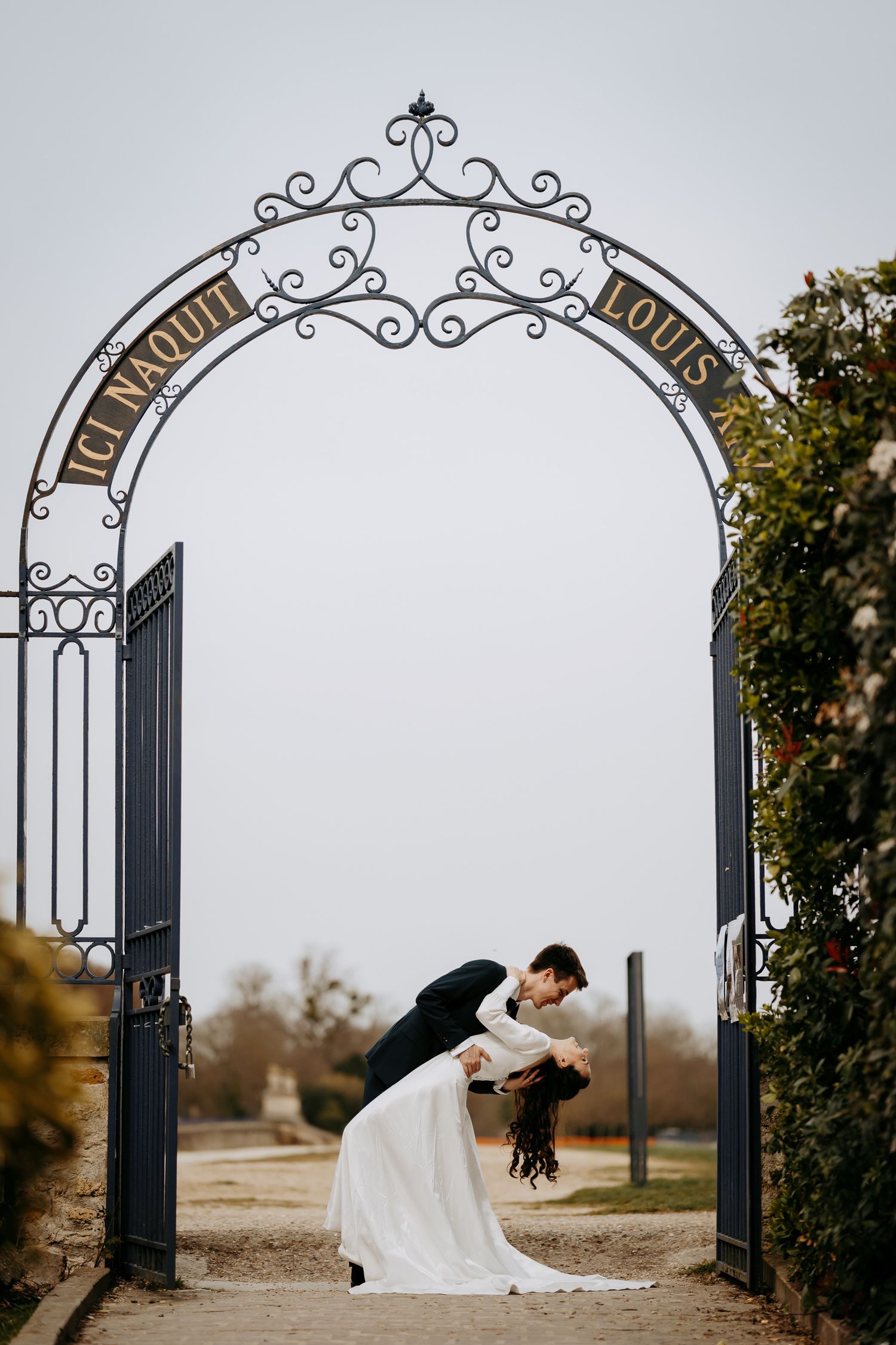 Romantic dip kiss under an arch at a destination wedding in Paris.