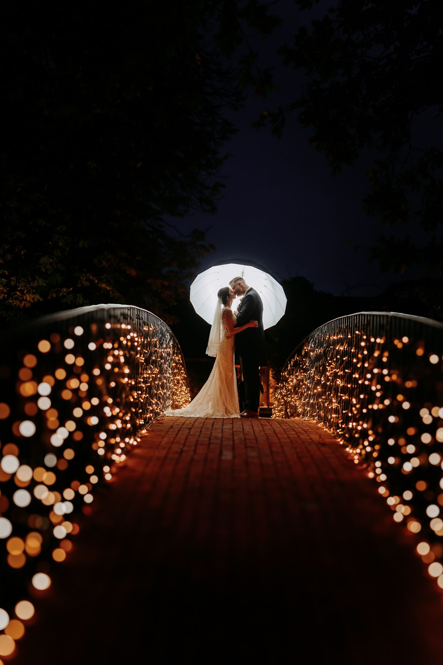 Couple lit up on the iconic bridge at Bassmead Manor, St Neots.