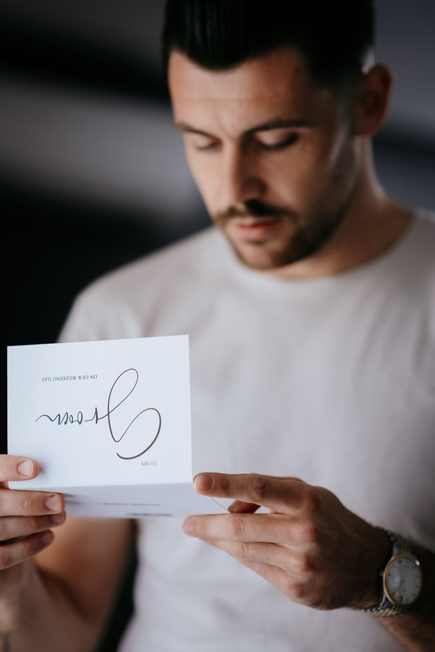 Groom reading a gift letter during prep at Swynford Manor.