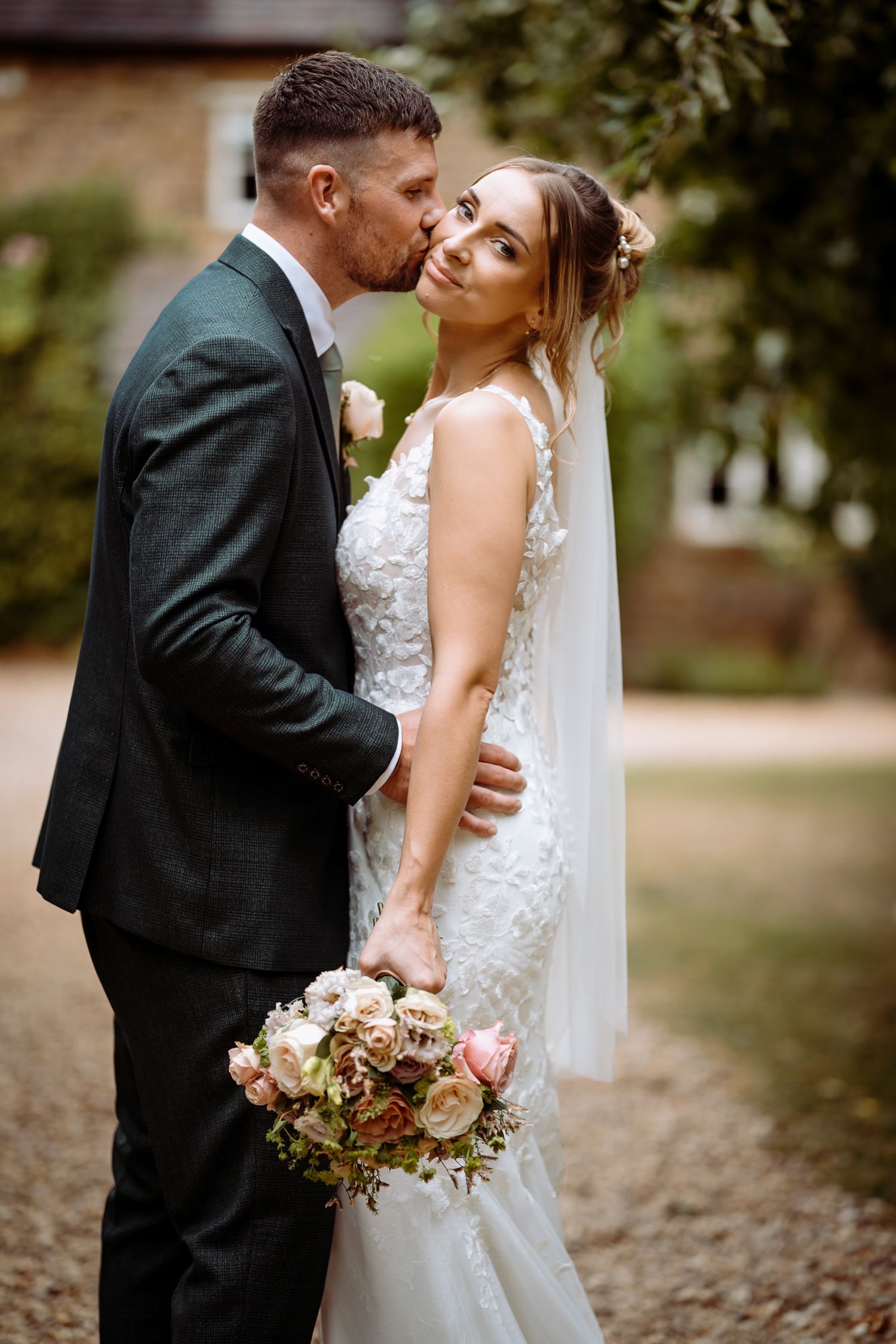 Relaxed couple posing with flowers at a Northampton wedding.