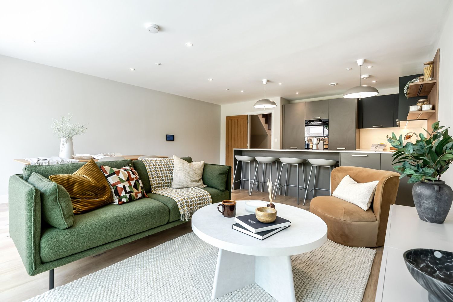 Modern Cambridge living room interior with green velvet sofa, white walls, and natural light streaming through large windows.