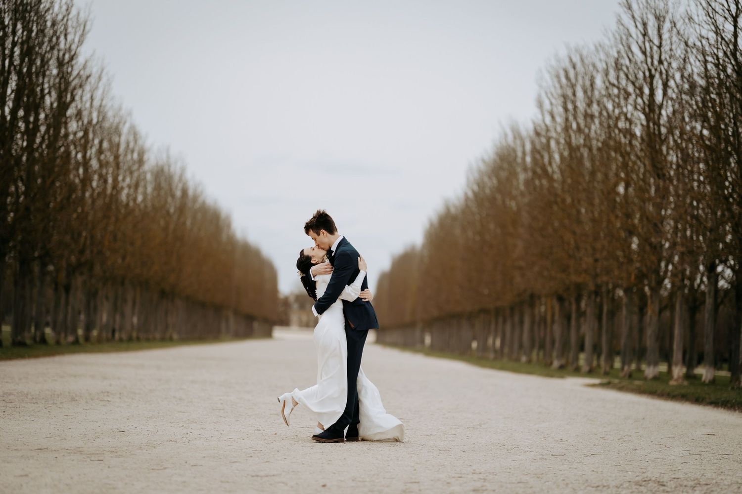 Artistic minimal pose wedding photography on a tree-lined path.