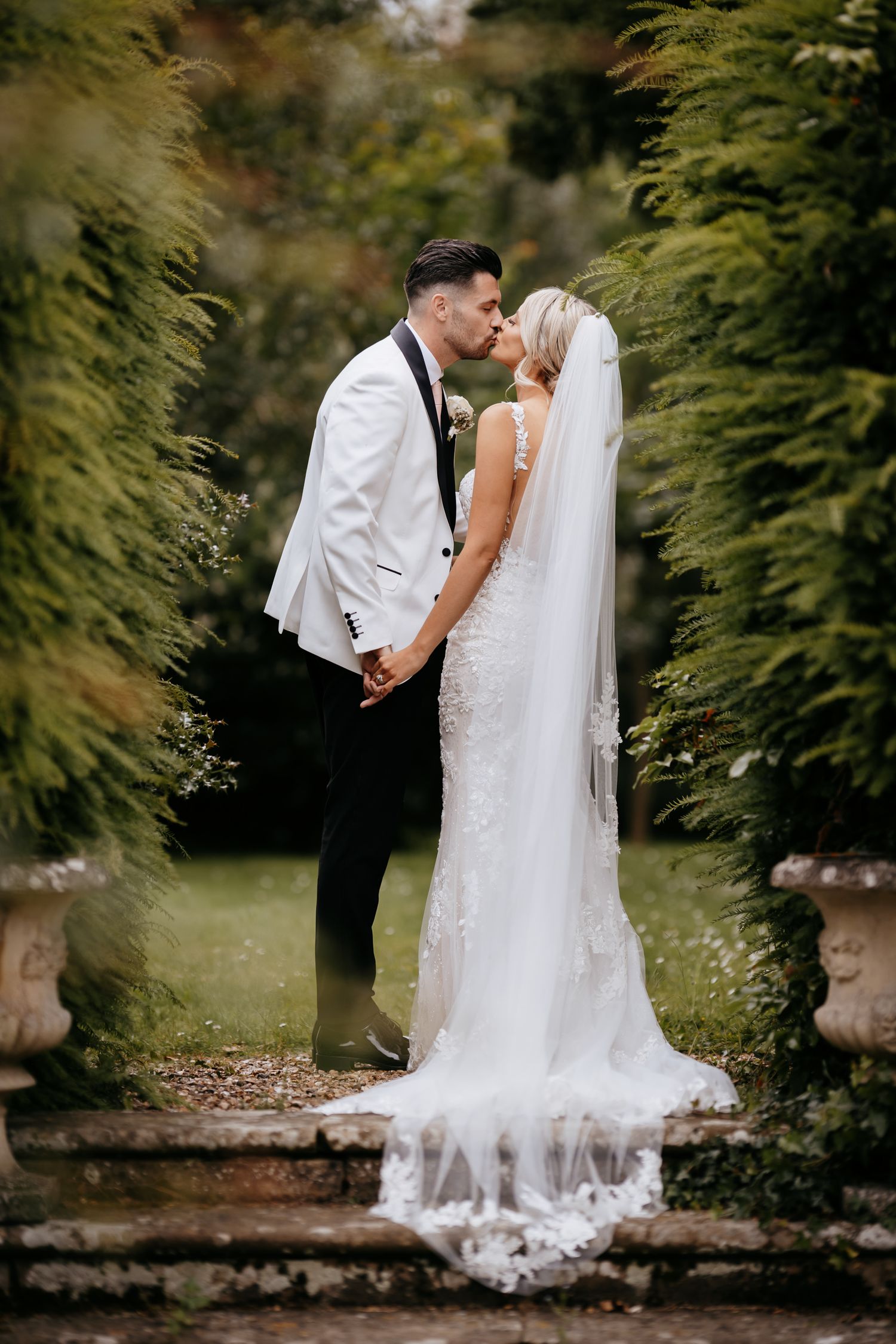 Couple's first kiss on outdoor steps with natural background.