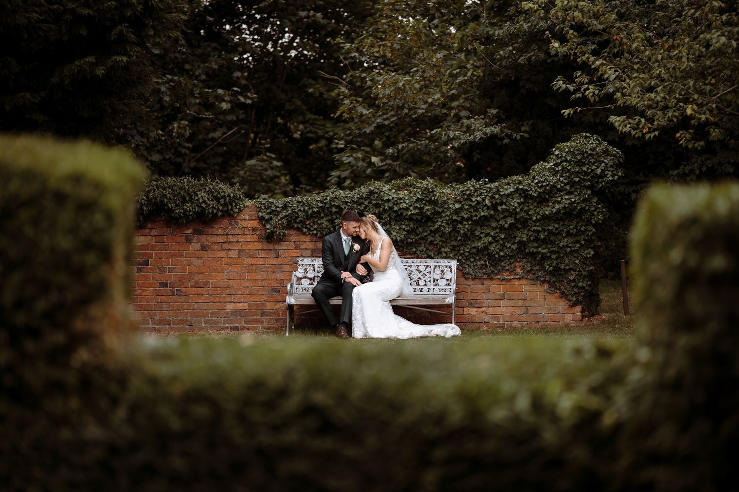 Candid wedding photography of a couple sharing a quiet moment on a bench.