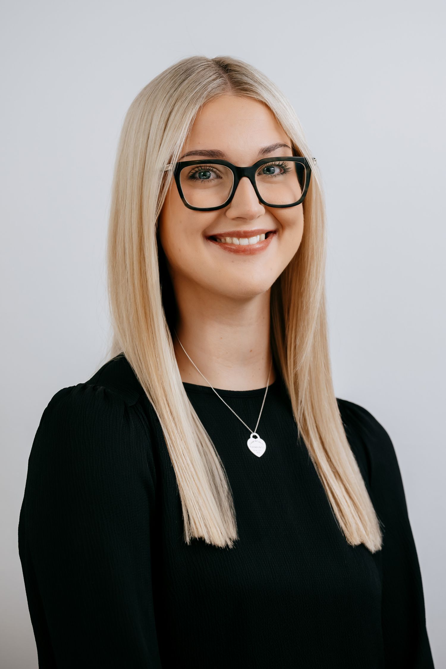 Professional headshots of a person with blonde hair and glasses wearing black against a white background.