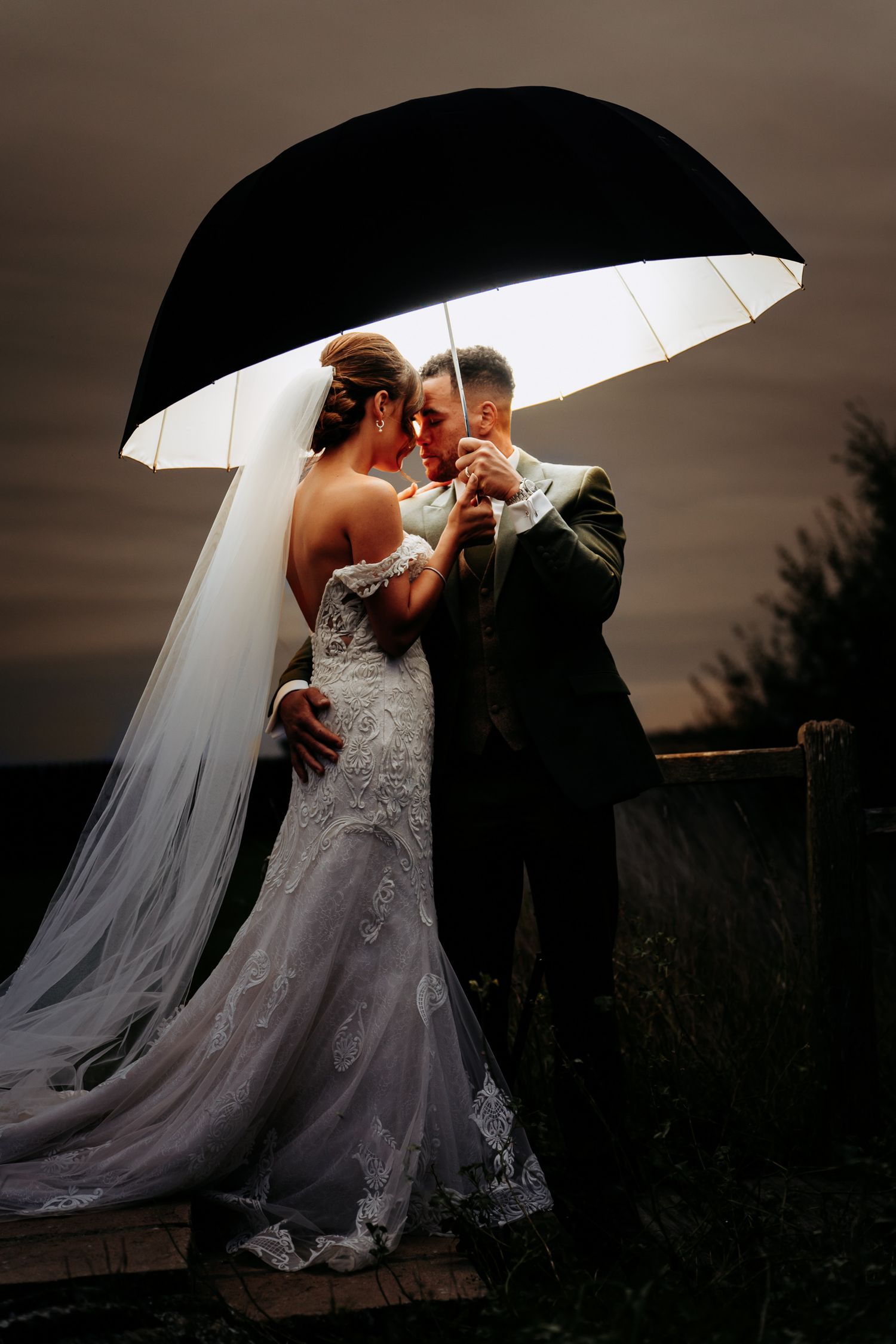 Wedding photo of a couple under an umbrella at Fulbourn Lodge.