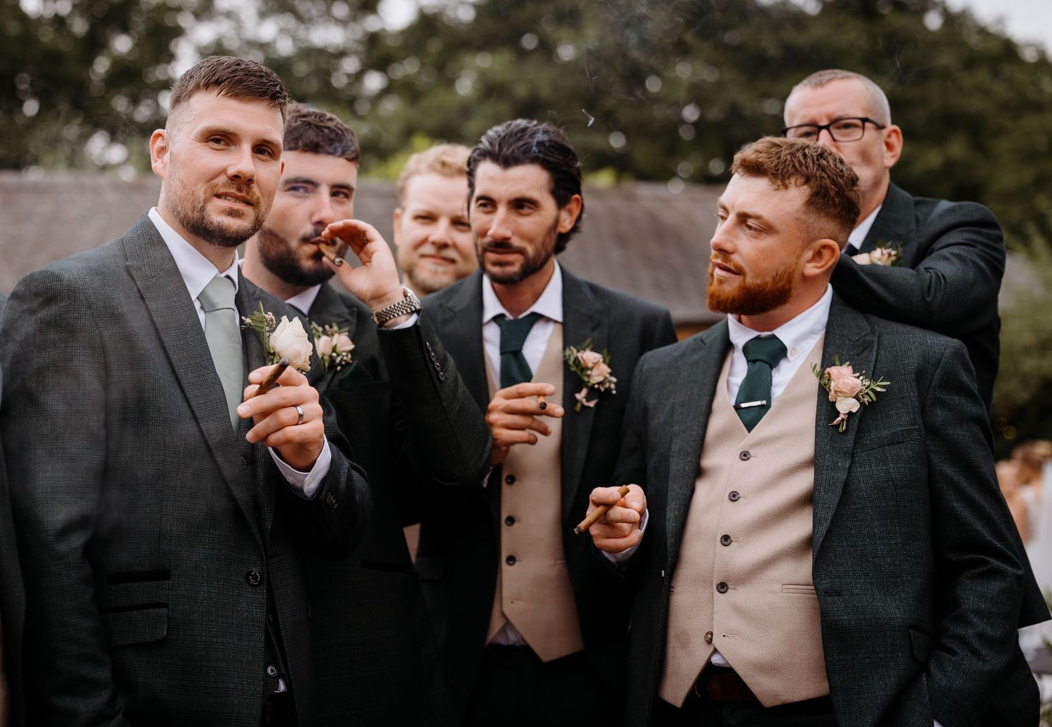 Groomsmen smoking cigars photo idea and celebrating at an outdoor wedding.