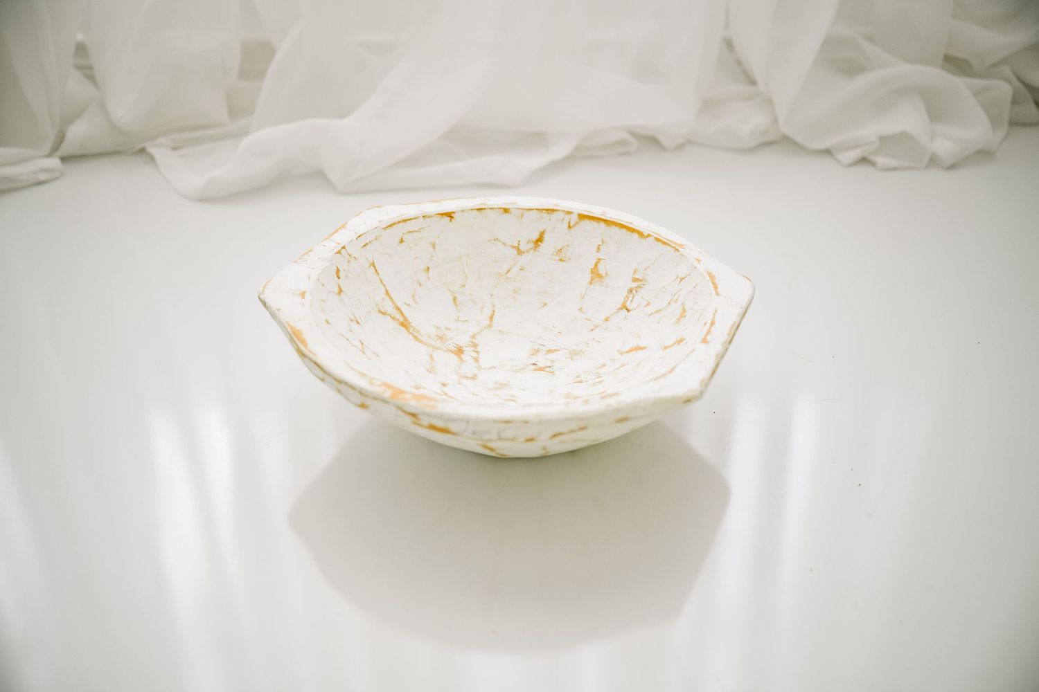 White bowl with gold marbled accents on a white surface.