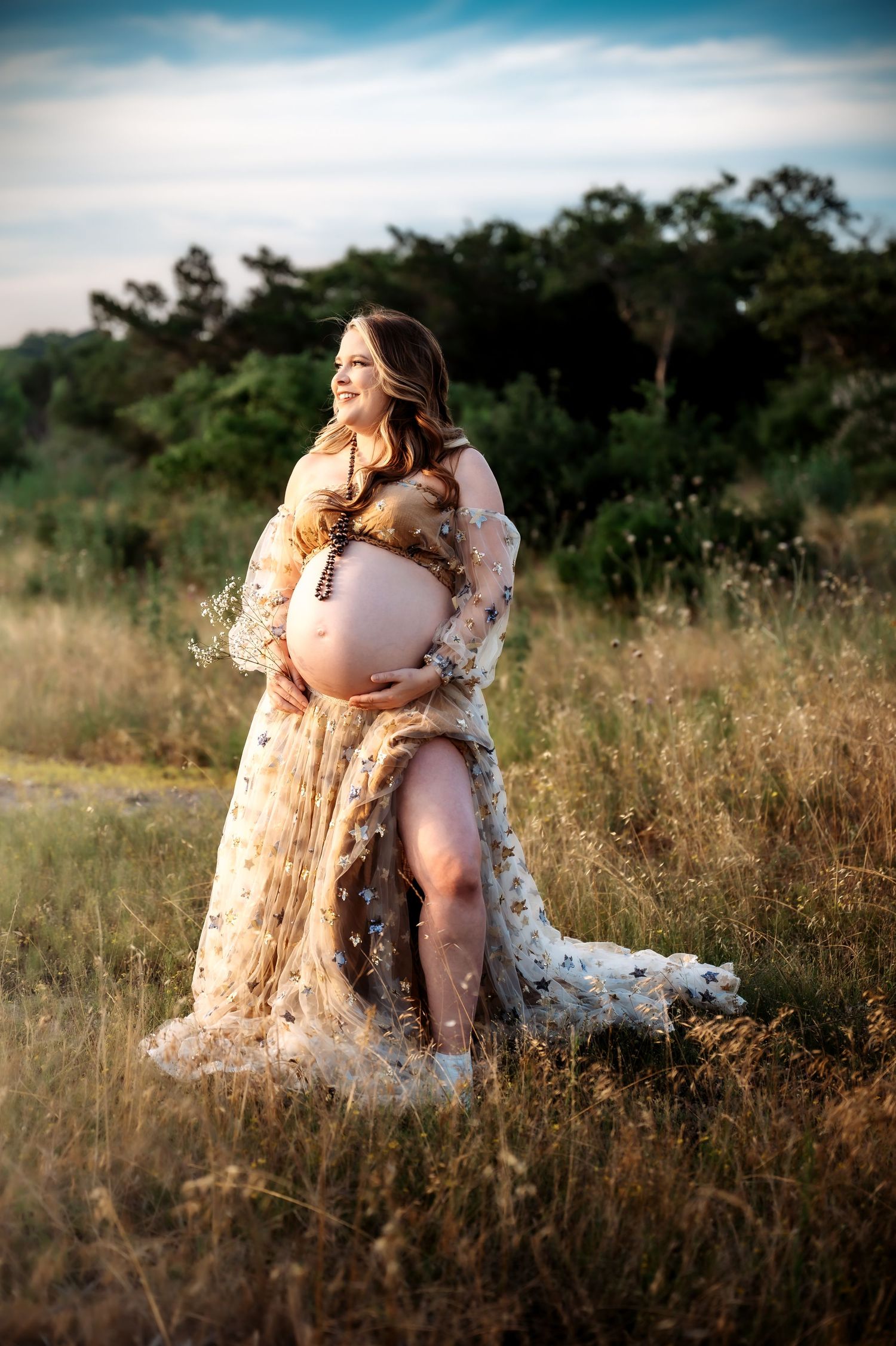 Maternity photo session in a golden field during sunset.