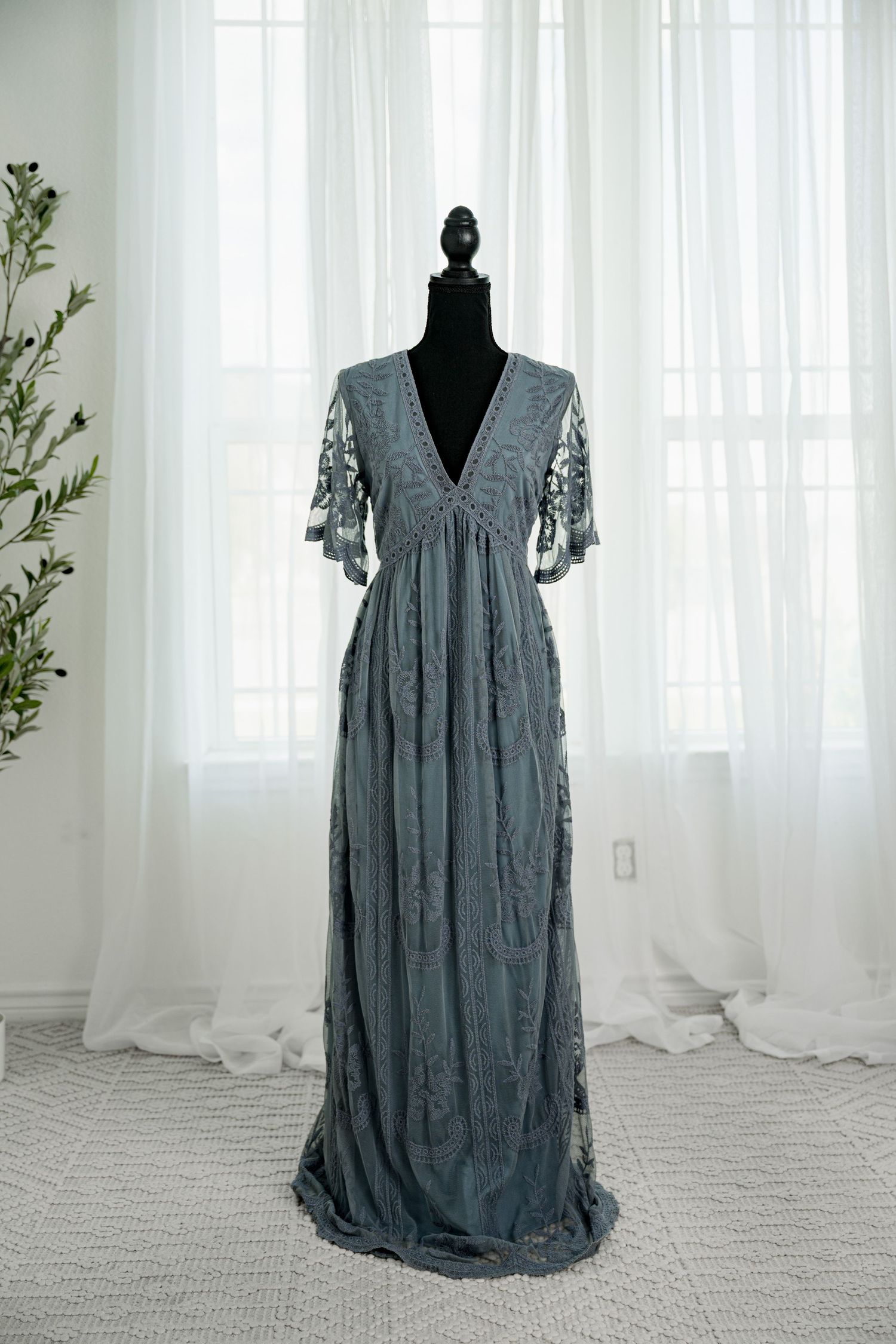 Dusty blue embroidered lace wrap maxi dress with flutter sleeves on a black mannequin.