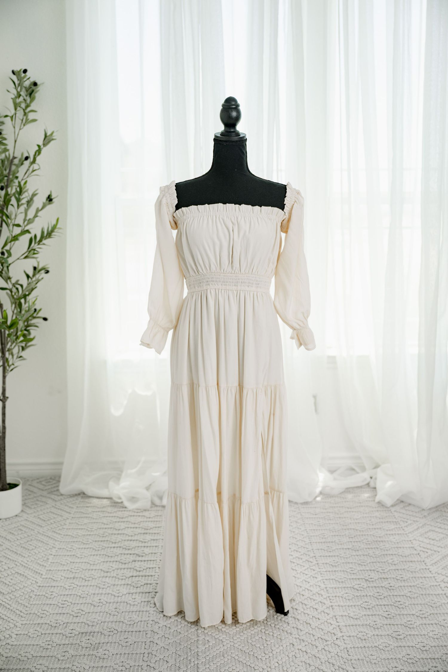 Cream off-shoulder long sleeve tiered maxi dress on mannequin.