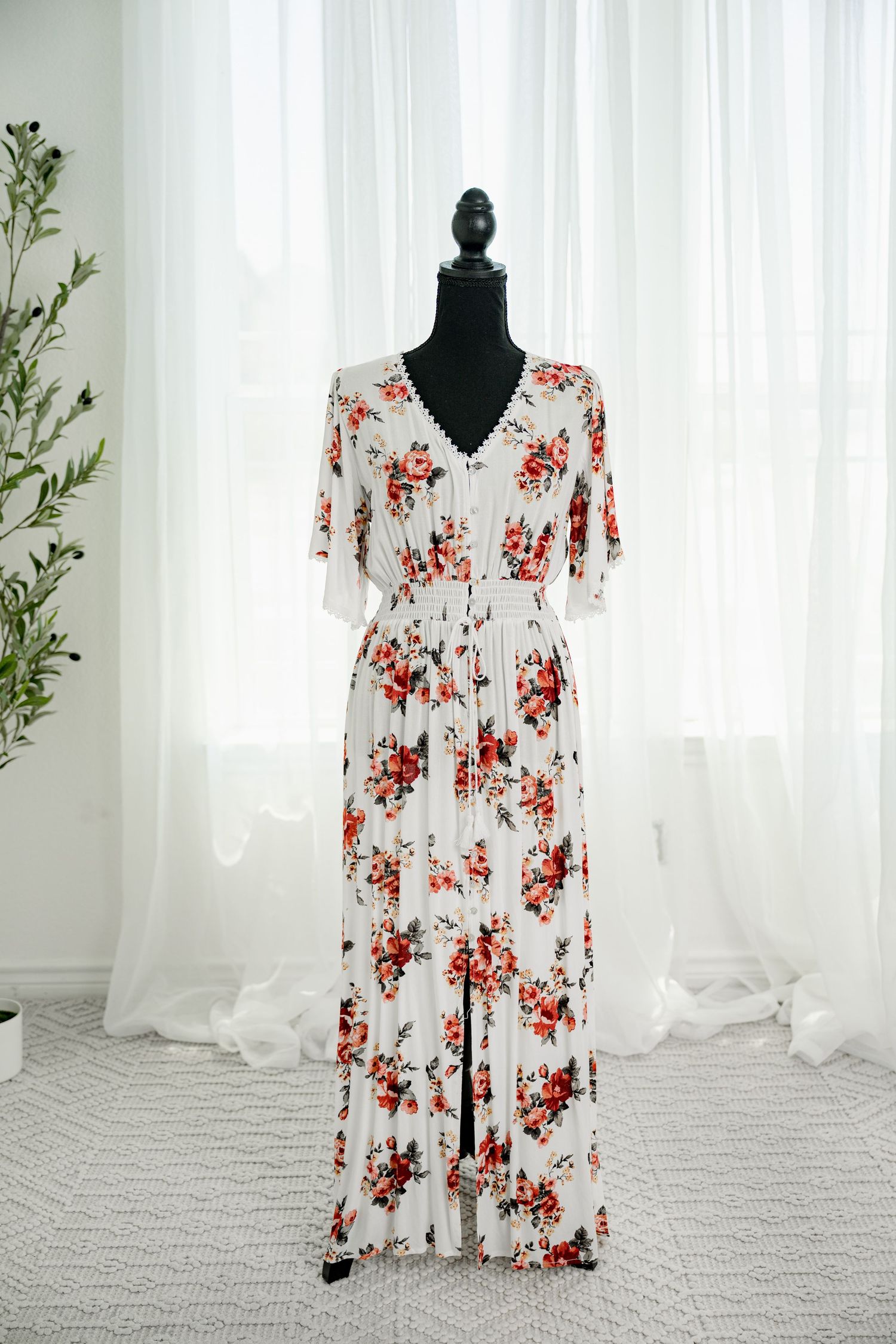 White floral maxi dress with red roses, V-neck, short sleeves, and flowing skirt on black mannequin.
