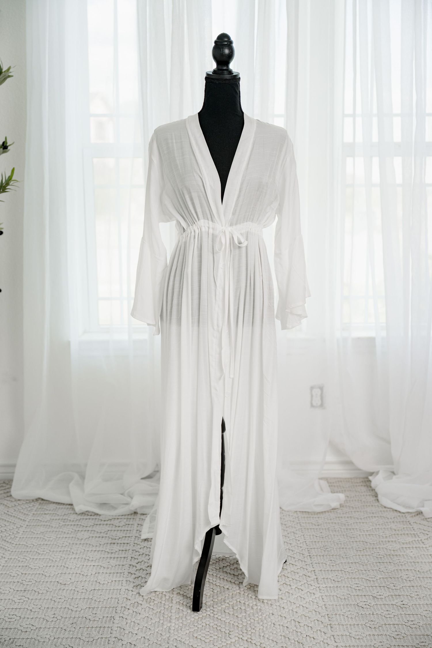 White sheer long sleeve belted robe gown with flowing train on a black mannequin.