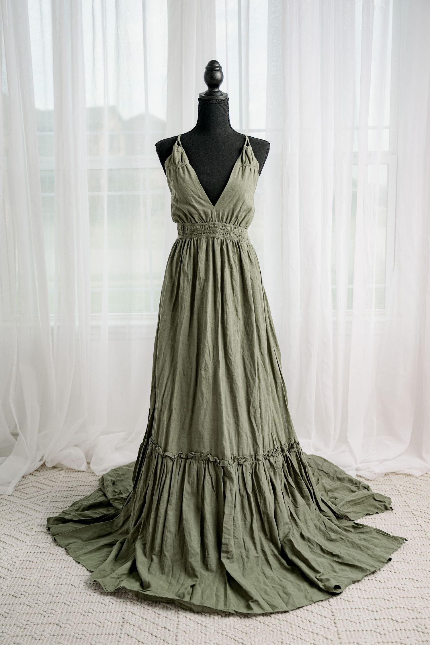 Olive green halter maxi dress with deep V-neck and tiered ruffle hem on black mannequin.