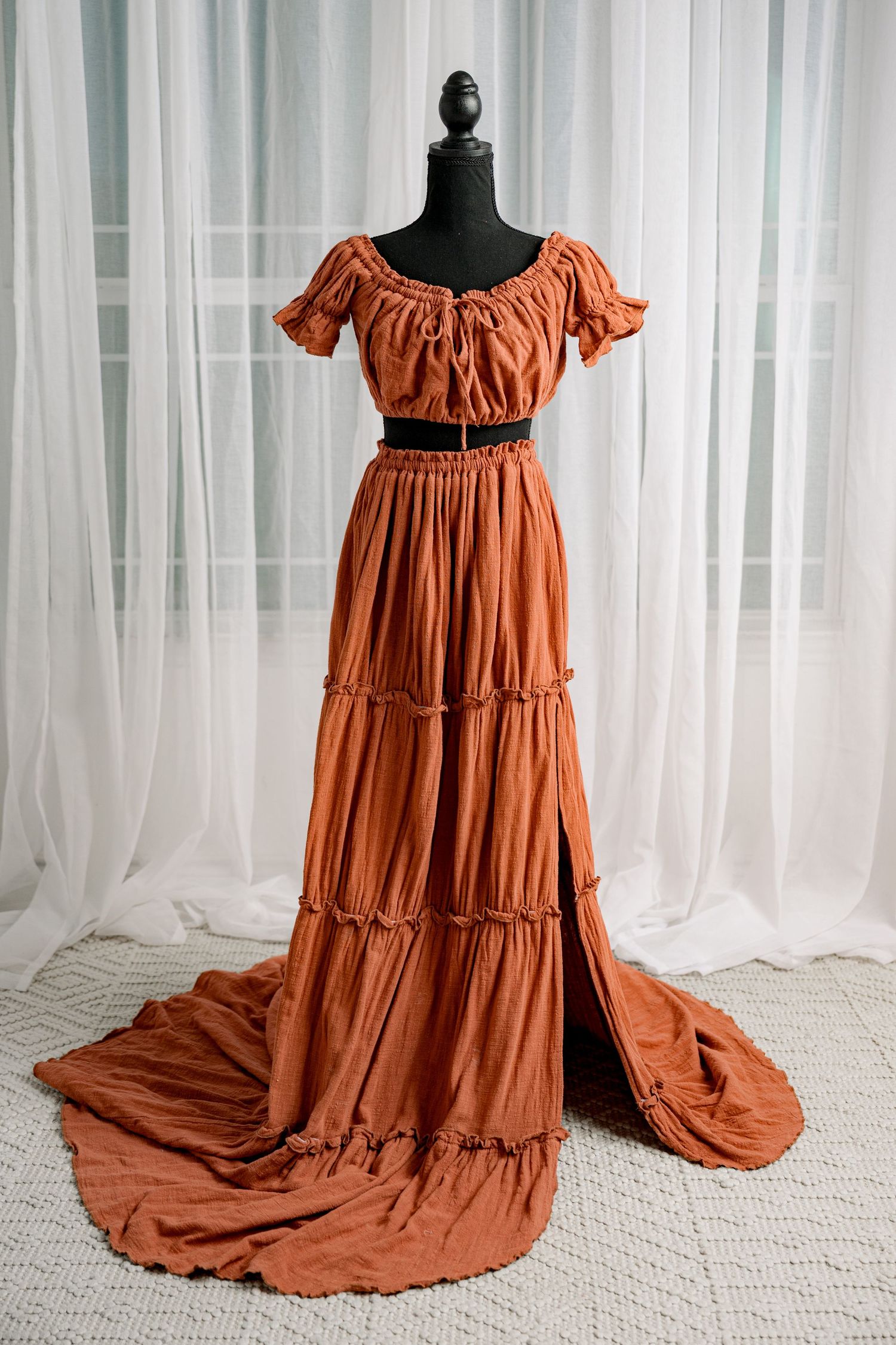 Burnt orange off-shoulder ruffled tiered two-piece maxi dress on mannequin.
