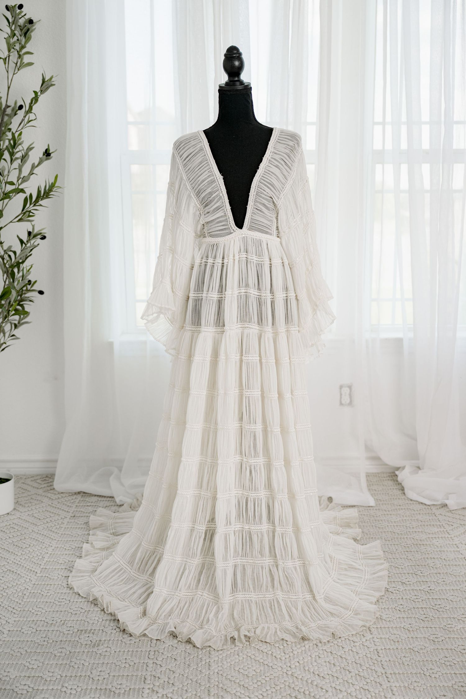 White deep V-neck long sleeve fringe tiered boho maxi dress on a black mannequin.