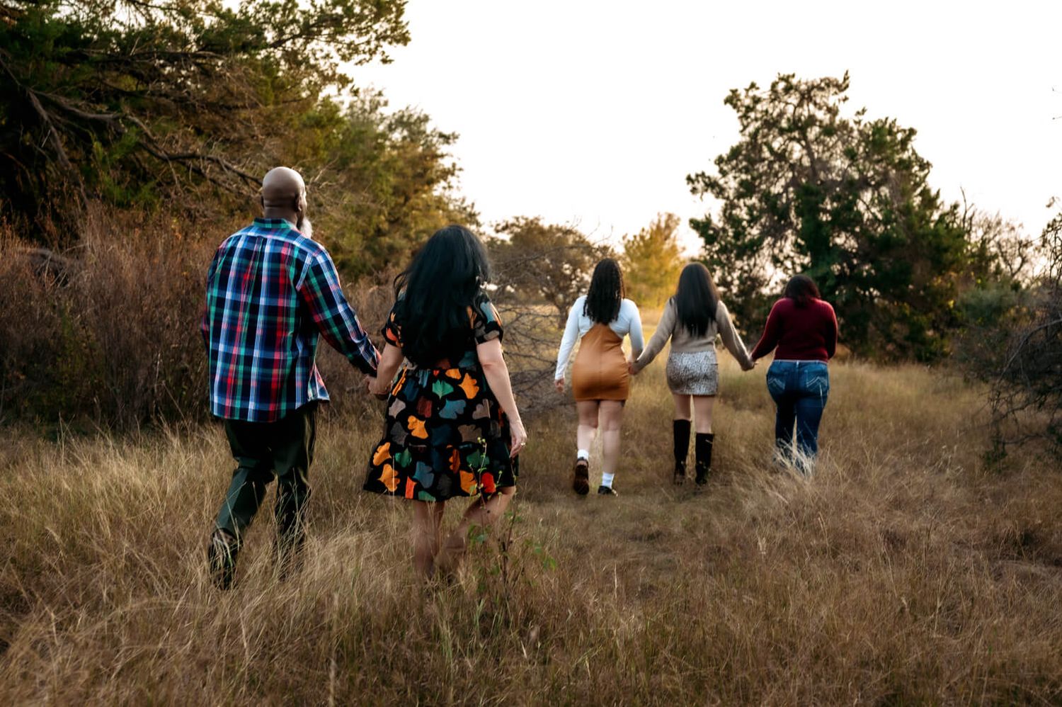 Group walking through golden field at sunset, captured from behind.